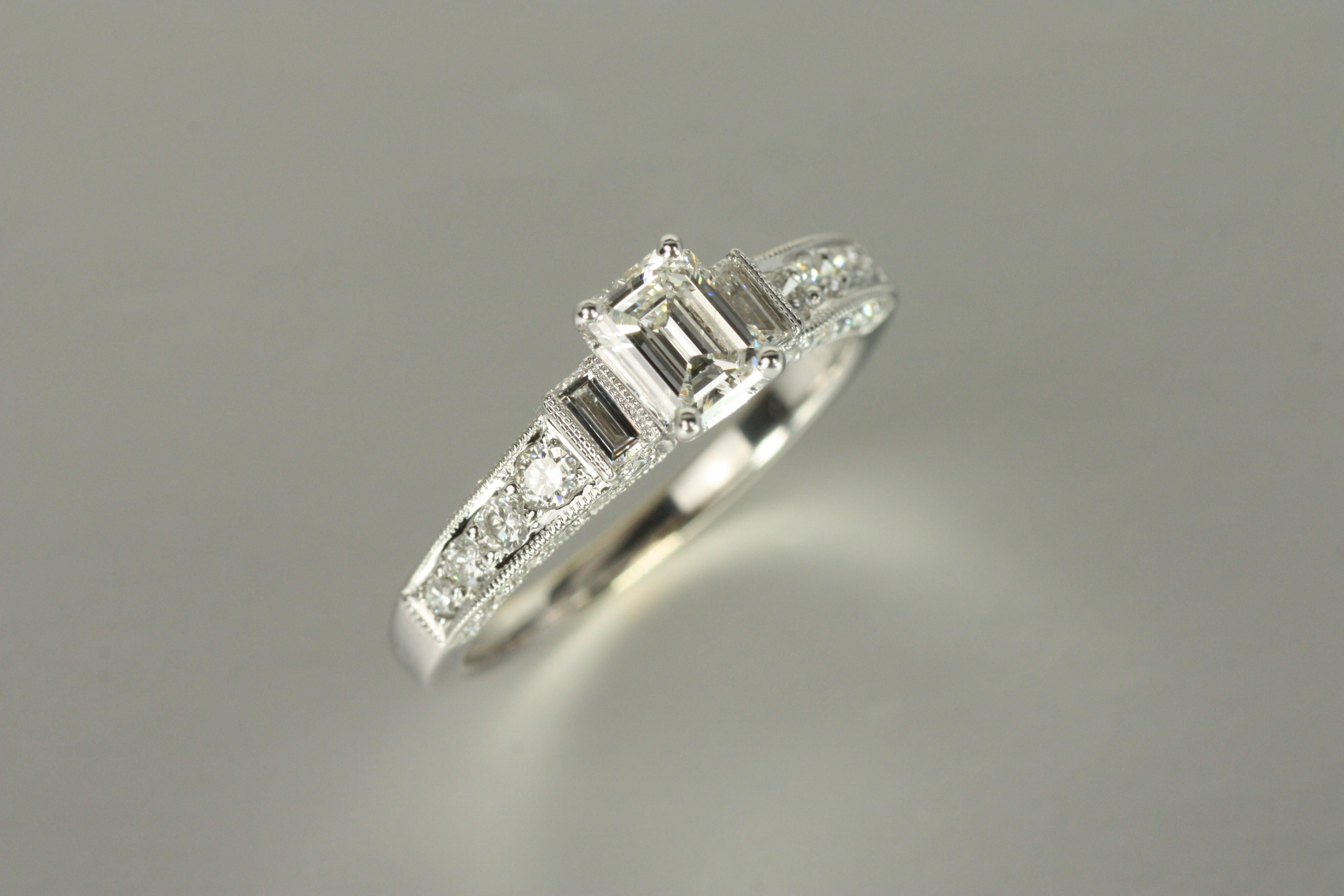 Per chi apprezza l'eleganza raffinata, questo anello di fidanzamento con più pietre offre un perfetto equilibrio tra influenza Art Deco e design contemporaneo. Il diamante centrale con taglio smeraldo da 0,48 carati è affiancato da diamanti a