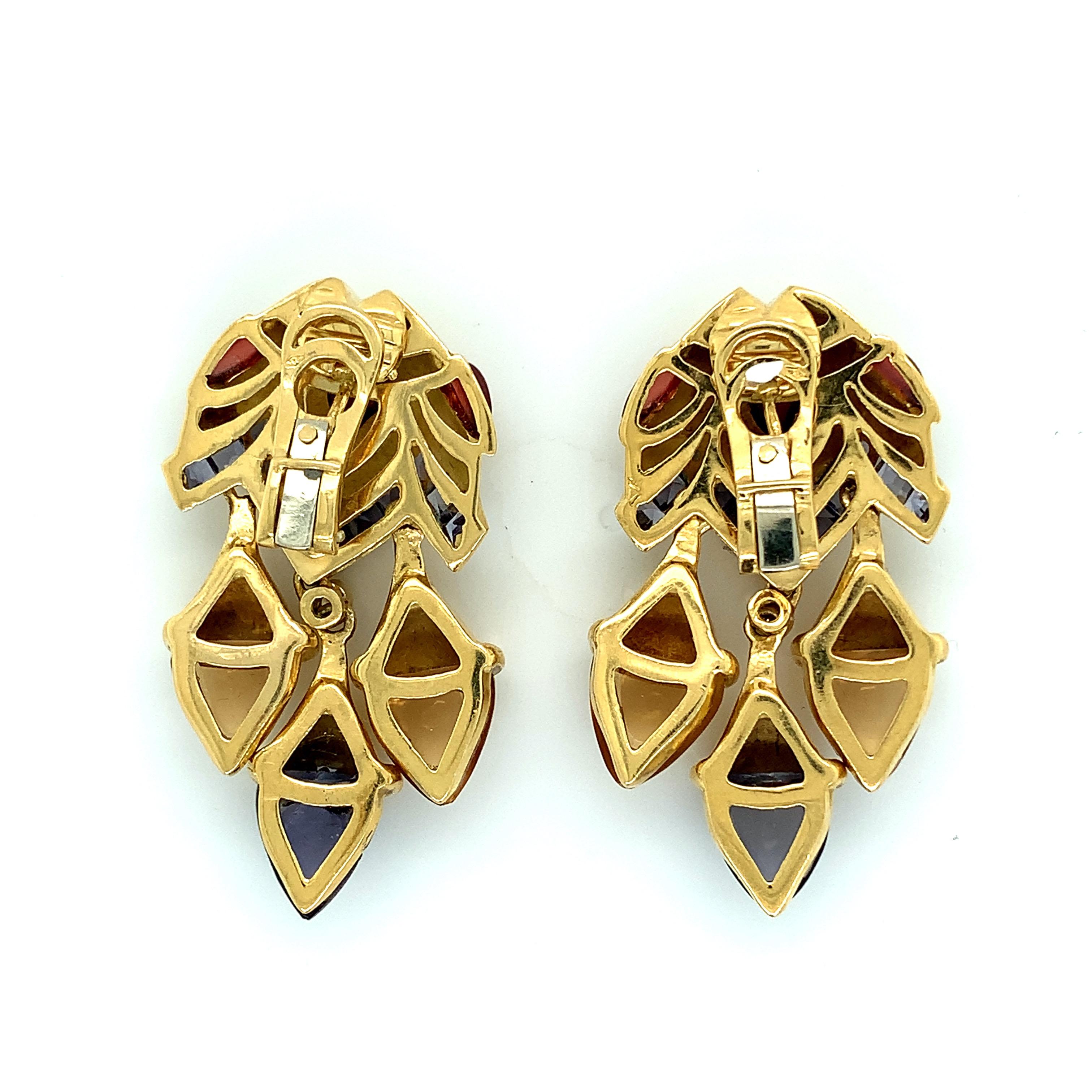A pair of fun multi-stone ear clips including sapphire, iolite, garnet, and citrine set on 18 karat yellow gold, with a creative fish motif. Total weight: 38.0 grams. Width: 1 inch. Length: 1.75 inch. 