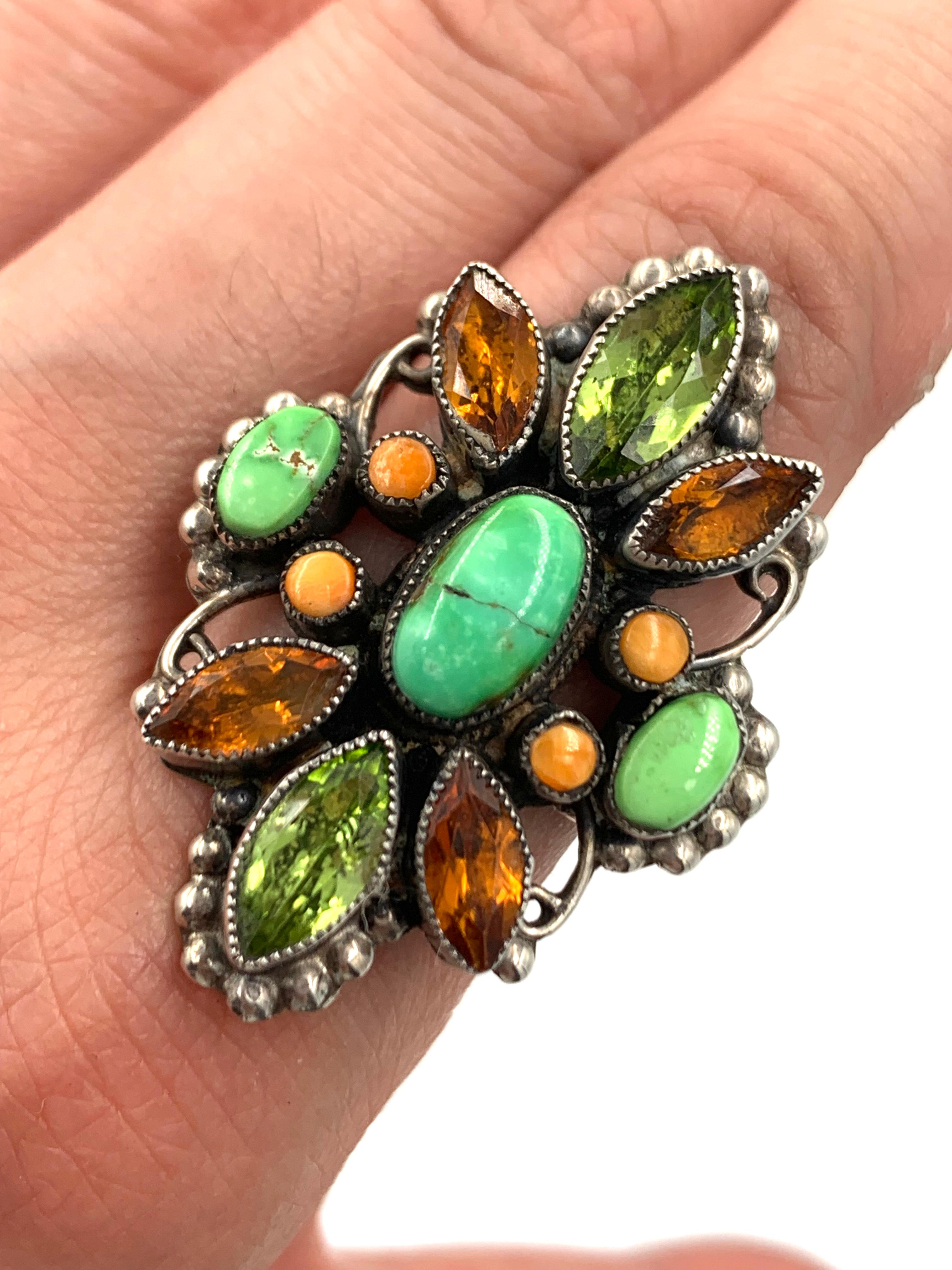 The ring has a 1/4” x 3/8” green turquoise cabochon in the center, which is surrounded by 2 faceted peridot, 4 faceted citrine stones, 4 orange spiny oyster rounds and 2 green turquoise stones. The entire ring is 1” x 1-1/2”. Ring size 7-1/4

About