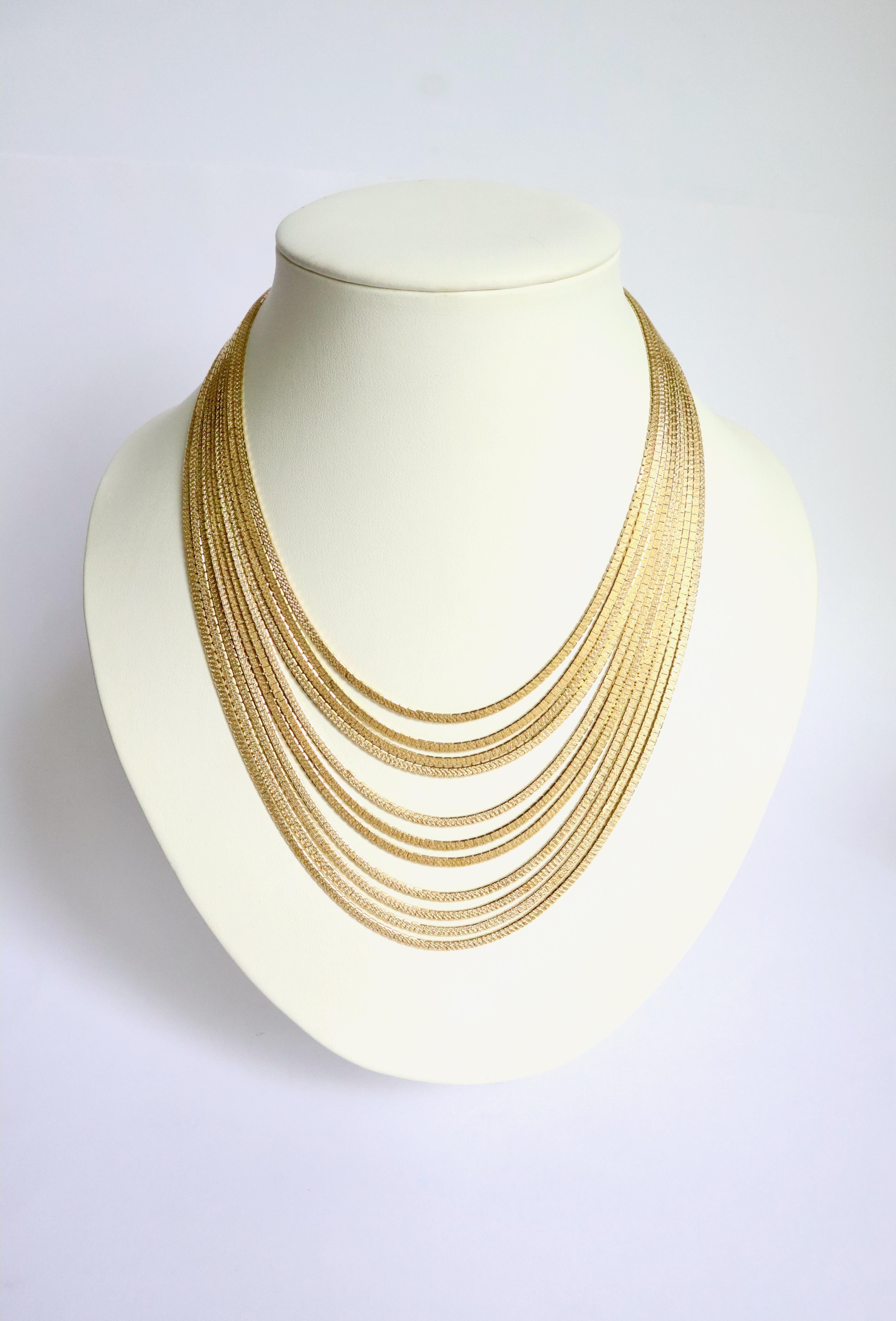 Mehrfädige Halskette aus 18 kt Gold. Er besteht aus 11 flachen, gegliederten Ketten aus satiniertem 18-karätigem Gelbgold. 
Es gibt einen Tab-Verschluss mit Sicherheits-Acht. 
Eagle-Kopfschlag. 
Nettogewicht: 149,2 g 
Länge von 41 bis 53 cm. 