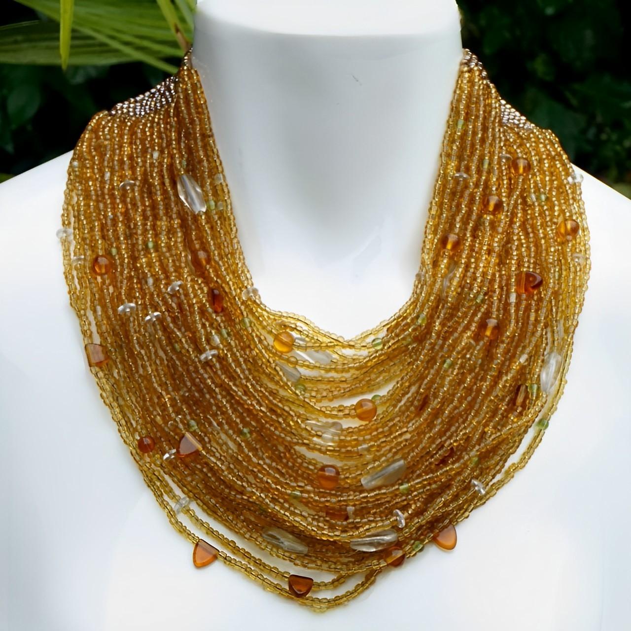 Magnifique collier de perles en verre ambré à plusieurs brins, avec des perles transparentes, vertes et ambrées foncées. Le dessus est orné d'un motif de perles d'ambre argentées tressées. Il y a quarante rangées de perles, la longueur la plus