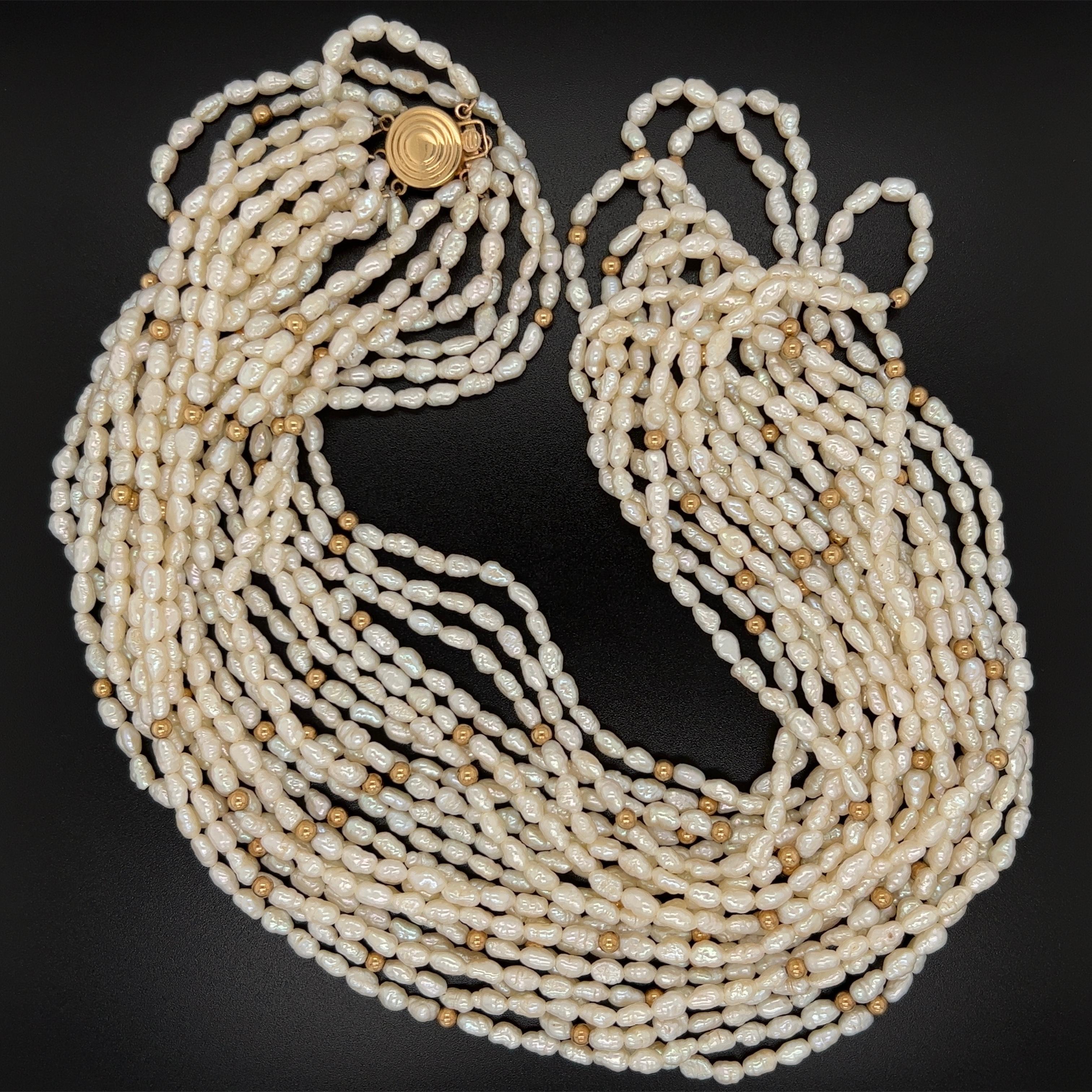 Einfach schön! Feine Barockperlen-Halskette mit 10 Strängen und Goldperlen, gehalten von einem runden Verschluss aus 14K Gelbgold. Ungefähre Länge der Halskette: 23