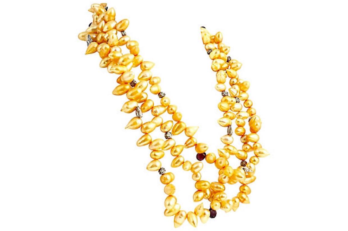 Triple-strand necklace featuring pear-shaped Chinese cultured pearls dyed in a golden hue accented with faceted garnets and silver-tone metal flowers and butterflies. Push button tongue in groove clasp.