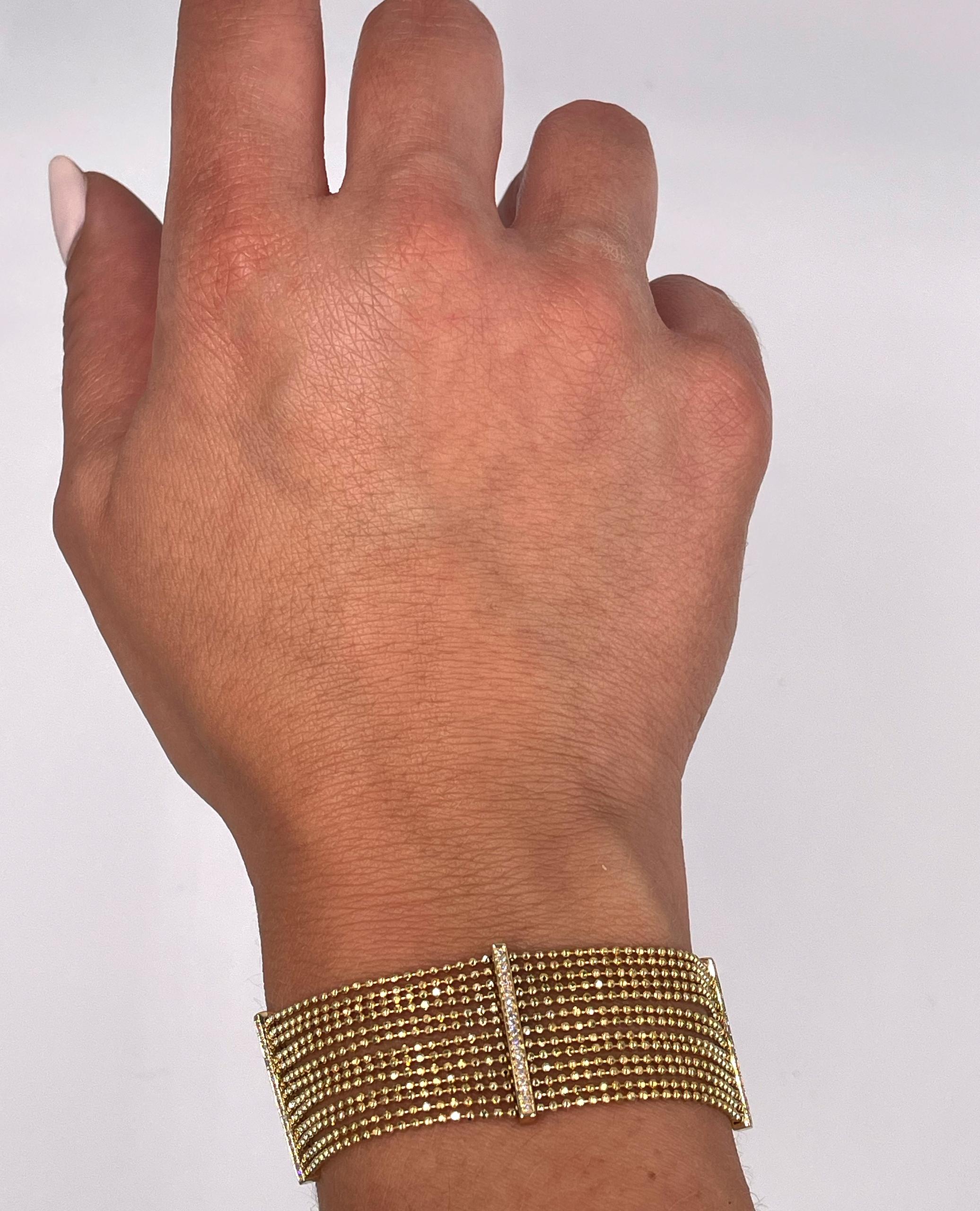 Bracciale regolabile a più fili in oro giallo 14K con 100 diamanti rotondi per un totale di 0,30 carati.

Questo bracciale è composto da più fili d'oro giallo 14K, disposti uno accanto all'altro a formare un'ampia fascia. Ogni filo è composto da