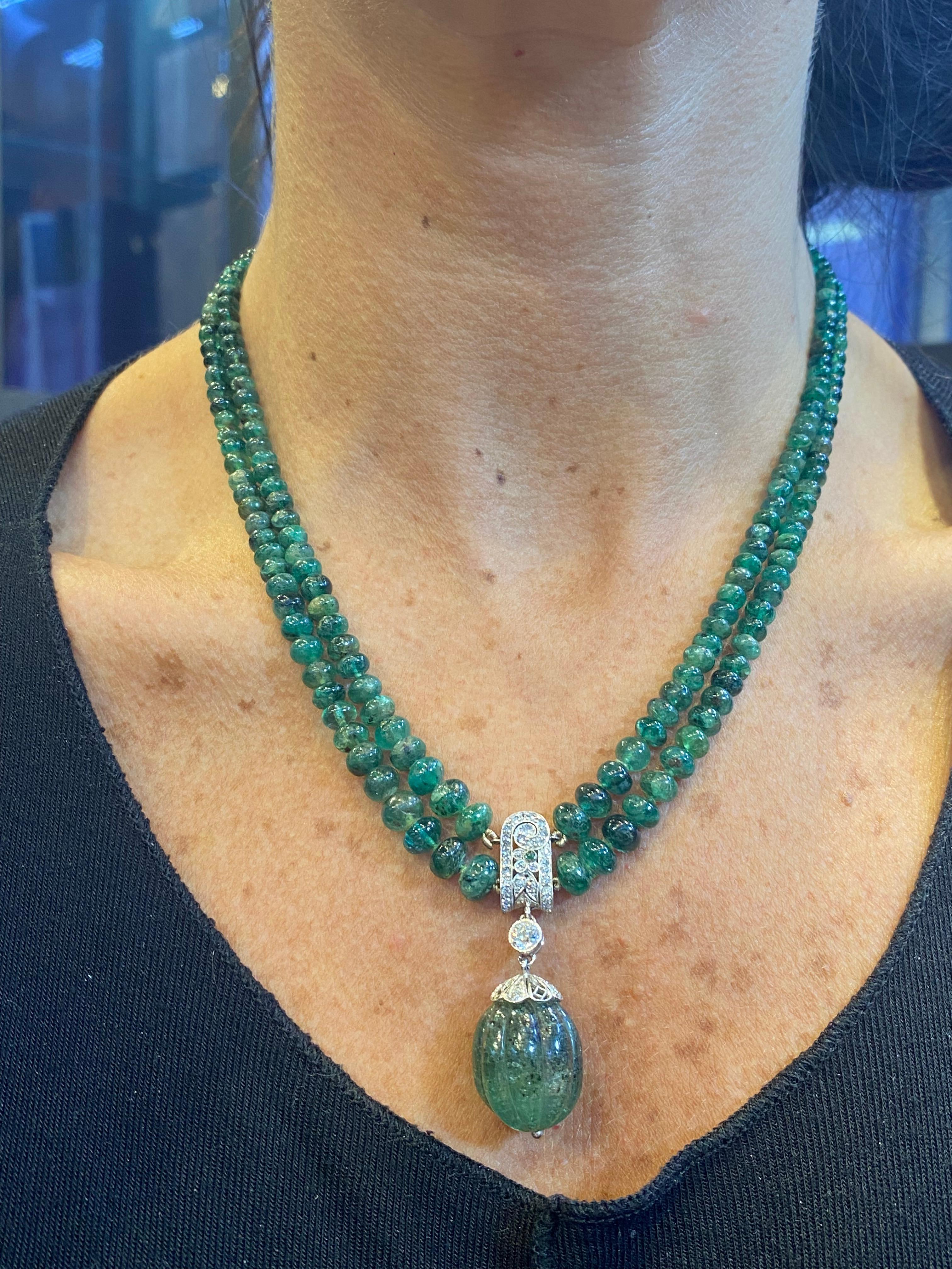 Multi Strand Emerald Bead Necklace

A necklace made of 2 strands of emerald beads suspending a pendant. The clasp and pendant consist of round cut diamonds set in platinum and 14 karat white gold.

The pendant is set with a carved emerald drop and