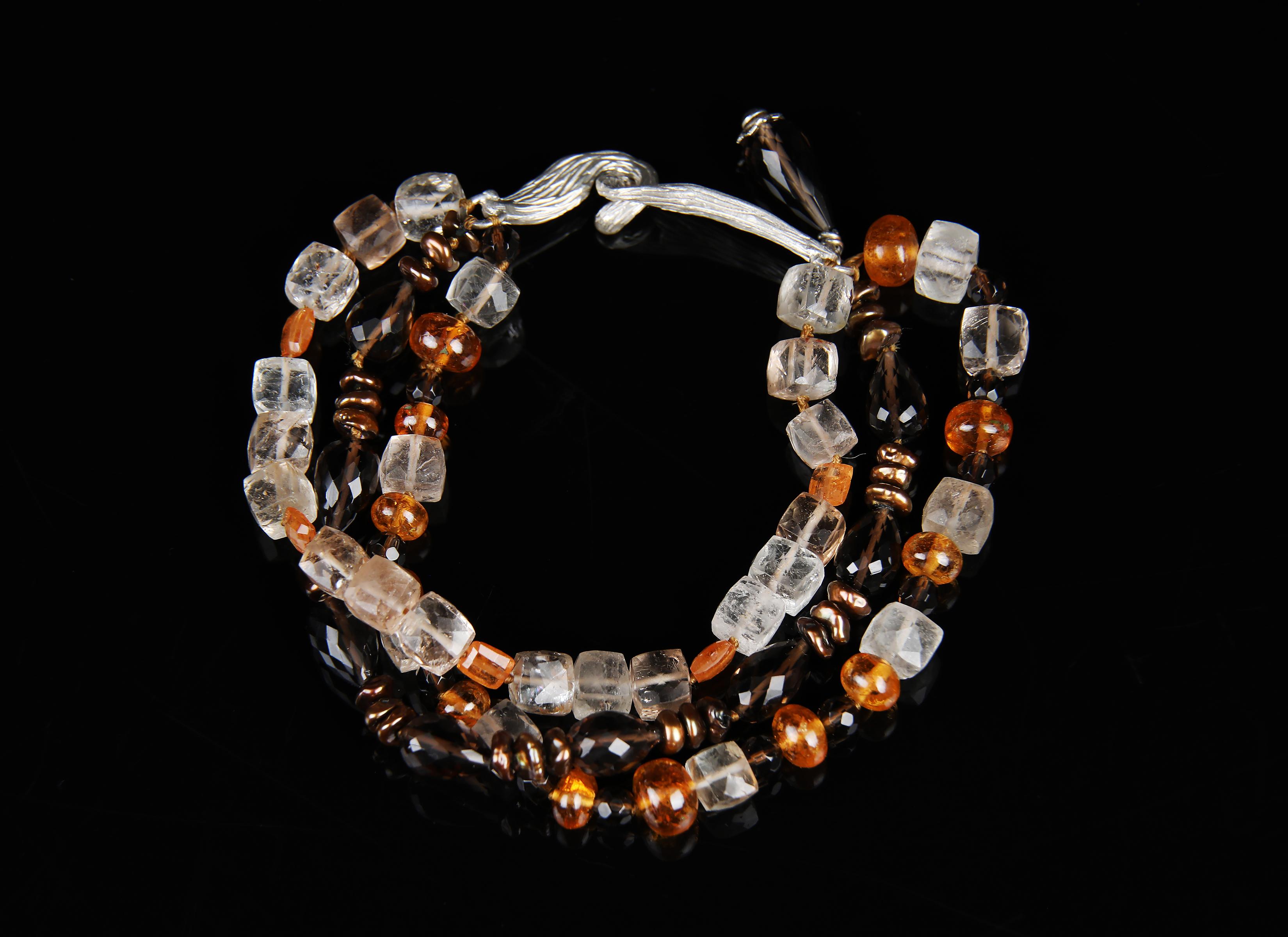 This precious topaz, mandarin garnet, keshi pearl, and silver three-strand bracelet is bold enough to stand alone. 