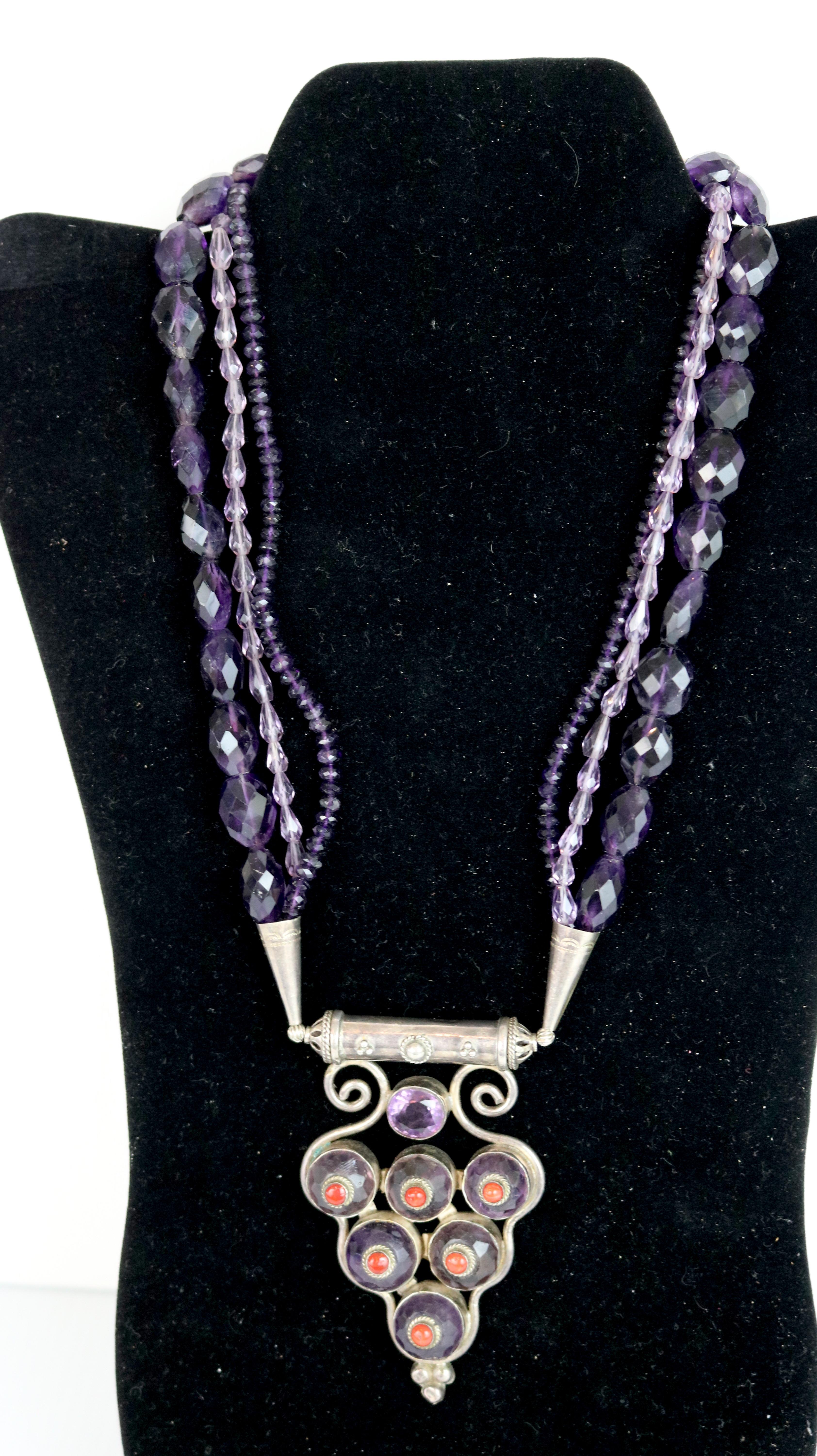  Couture Artisan One of a Kind Necklace- 
3 Strand Multi- Cut Amethyst Strands- with a Gorgeous Hanging Curvilinear Pendant  of an Amethyst Cabachon Setting with Center Coral Stones in Sterling Silver Setting
and clasp.
A Gorgeous Statement Necklace