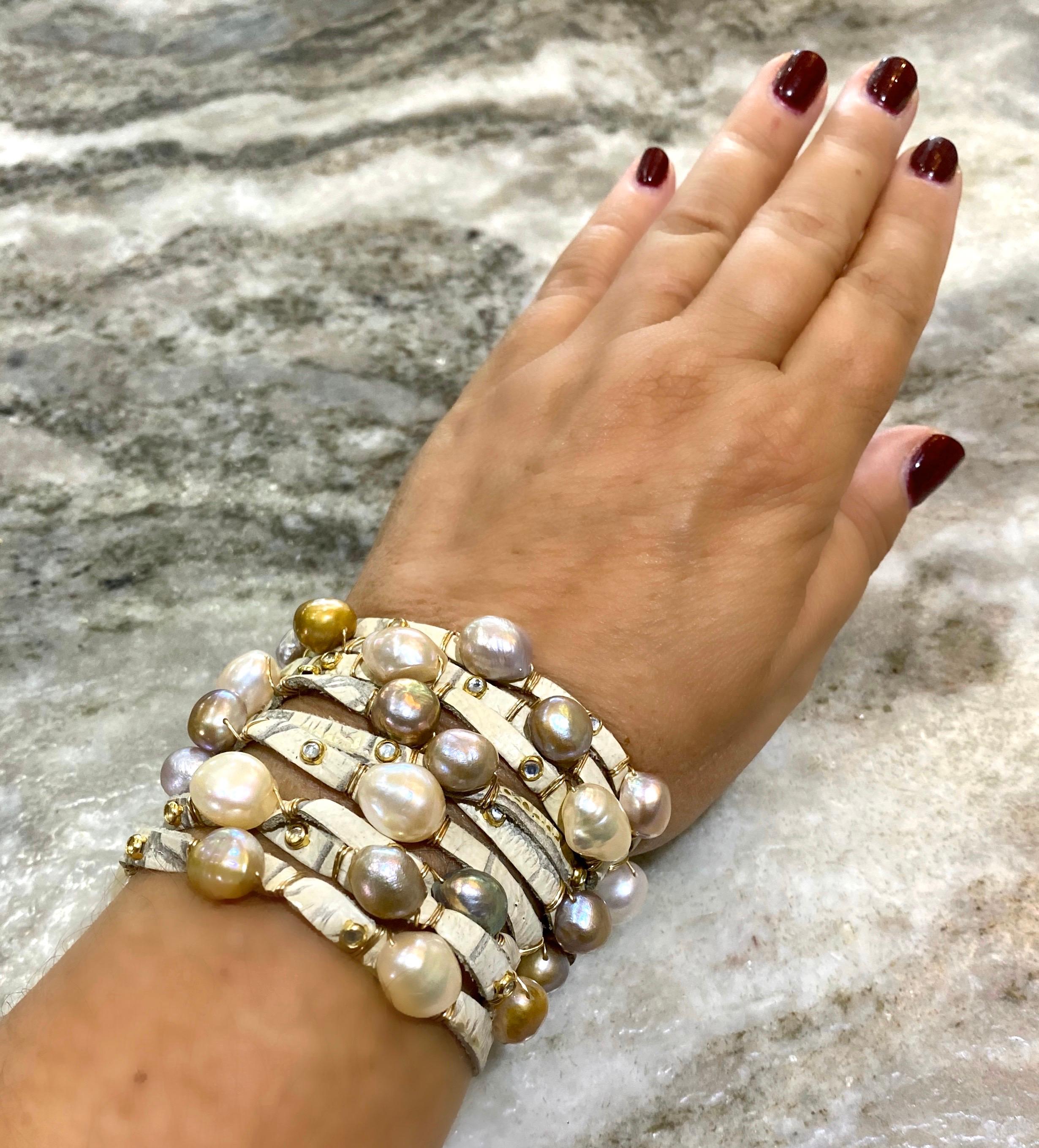 Bijoux De Mer signature leather cuff is adorned with naturally colored, baroque freshwater and Edision pearls hand-wired in 14k gold.  The cuff itself is a cream colored, embossed crocodile leather, and is studded with sparkly bezel-set crystal