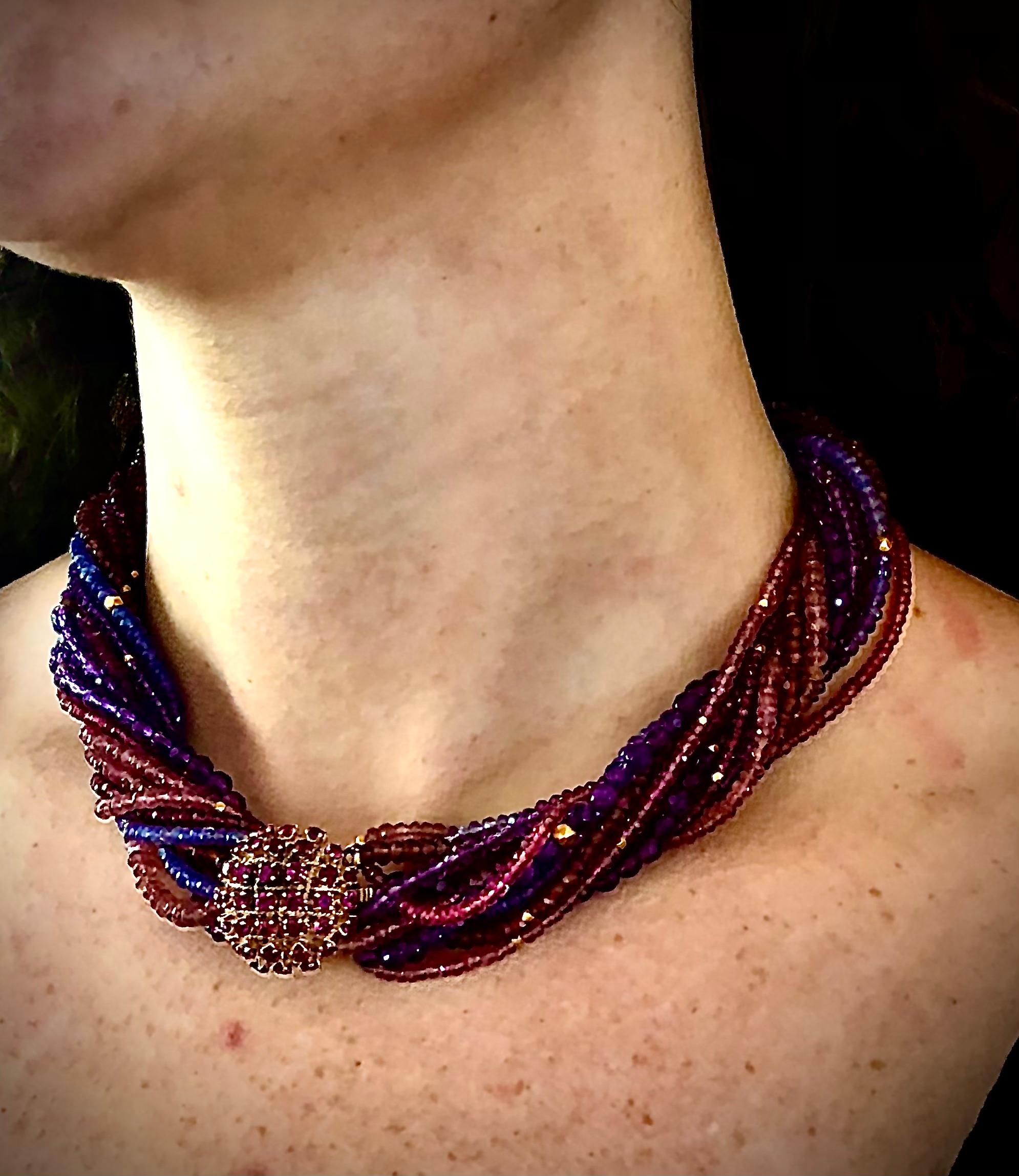 Multiple strand (8 strands plus) torsade necklace.
Amythest, tourmaline, iolite with 18kt gold geometric accent beads. 18kt gold and ruby set box clasp. 16.5” long .