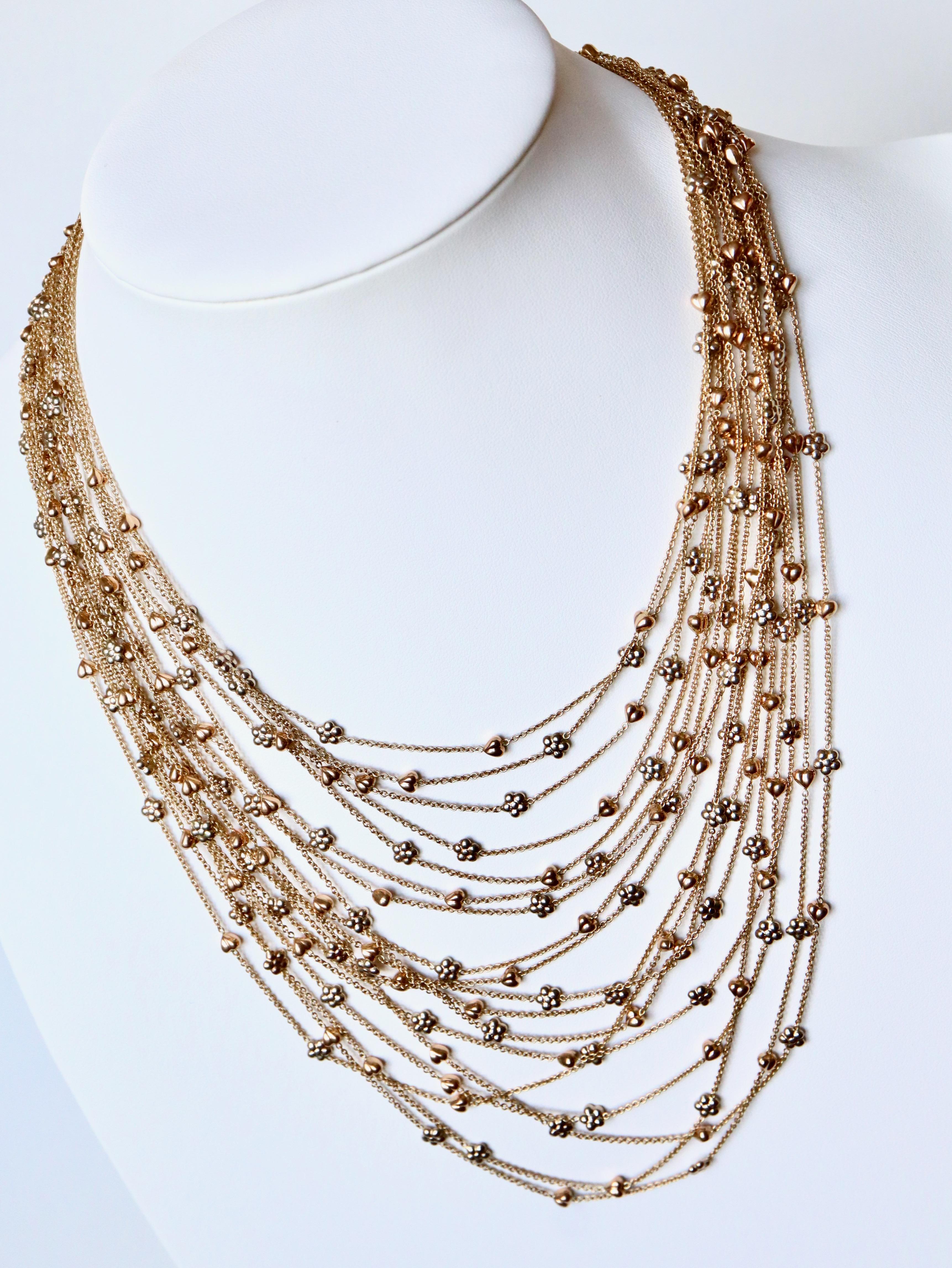 Collier multibrins en or 18 carats bicolore composé de 18 fils d'or jaune avec des motifs de cœurs en or rose et de fleurs en or jaune sur les brins. 
Fermoir à languette. Longueur 42 cm au plus court
Marqué 750 et poinçon en or 18 carats
Poids net