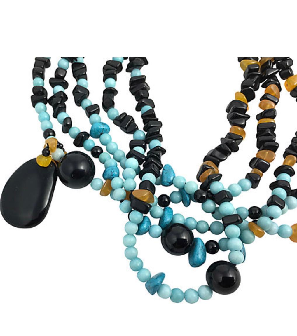 Five-strand necklace featuring round and freeform reconstituted turquoise beads strung with onyx and amber beads accented with a flat onyx drop. Clasp marked 
