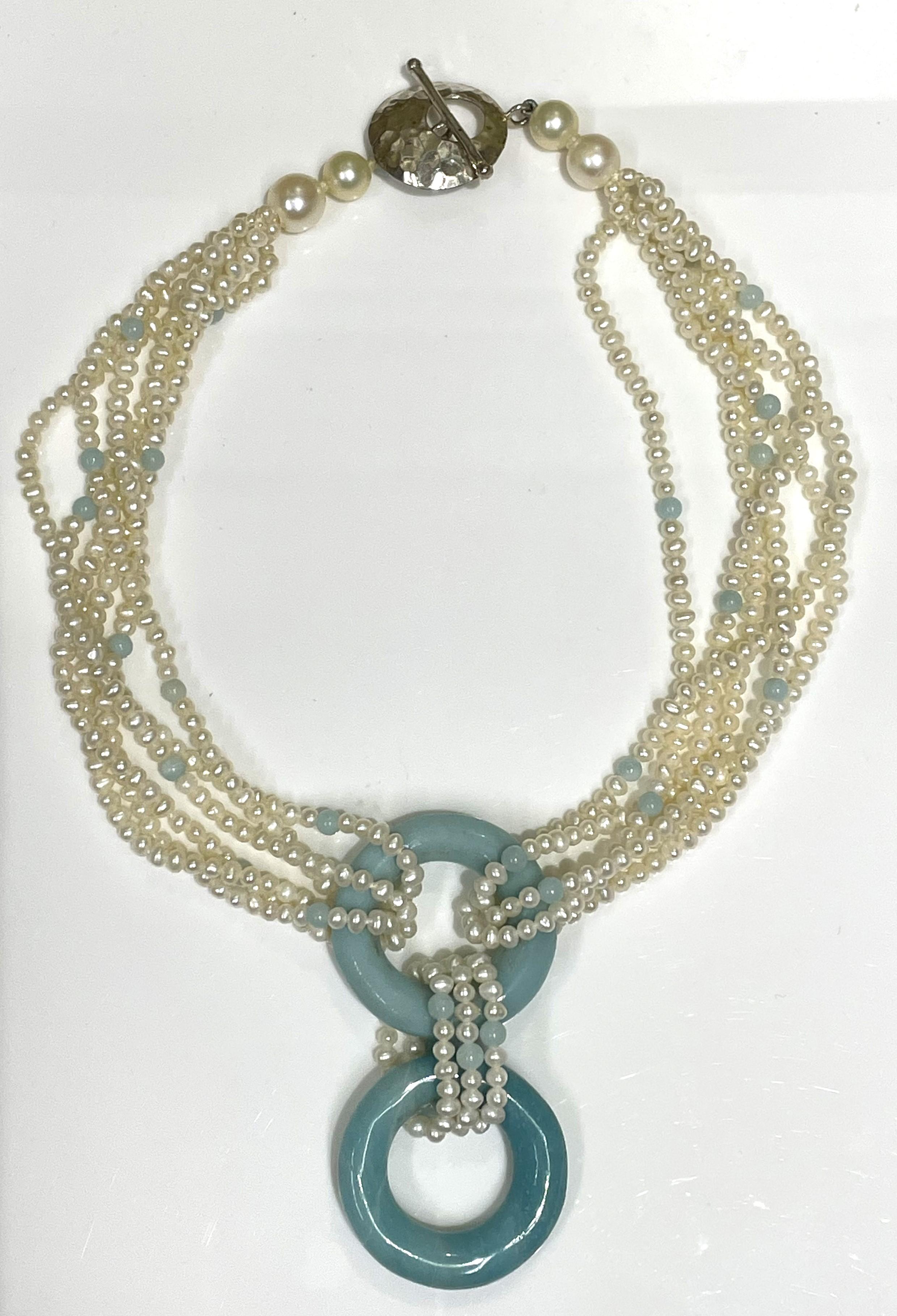 This one-of-a-kind piece will grab attention with any outfit!
6-strand freshwater pearl necklace with turquoise beads.  Center has two large turquoise, open circle pieces connected by pearl strands.  
Silver toggle clasp with hammered