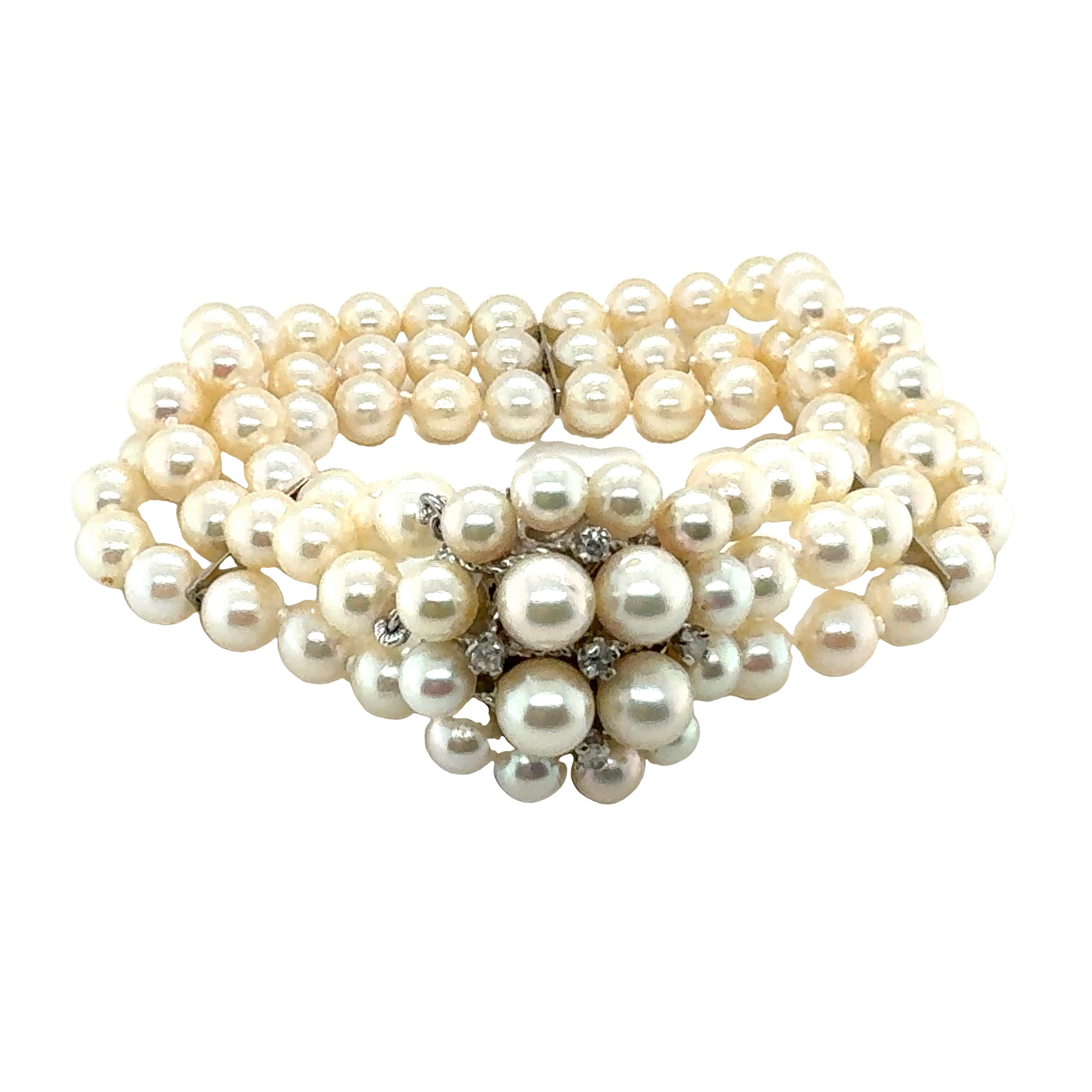 One multi-strand pearl bracelet in 14K white gold featuring three strands of white, round cultured pearls measuring 6.00-6.50 millimeters in diameter on average with A rating. Also features a round clasp enhanced by pearls and diamond accents of 5