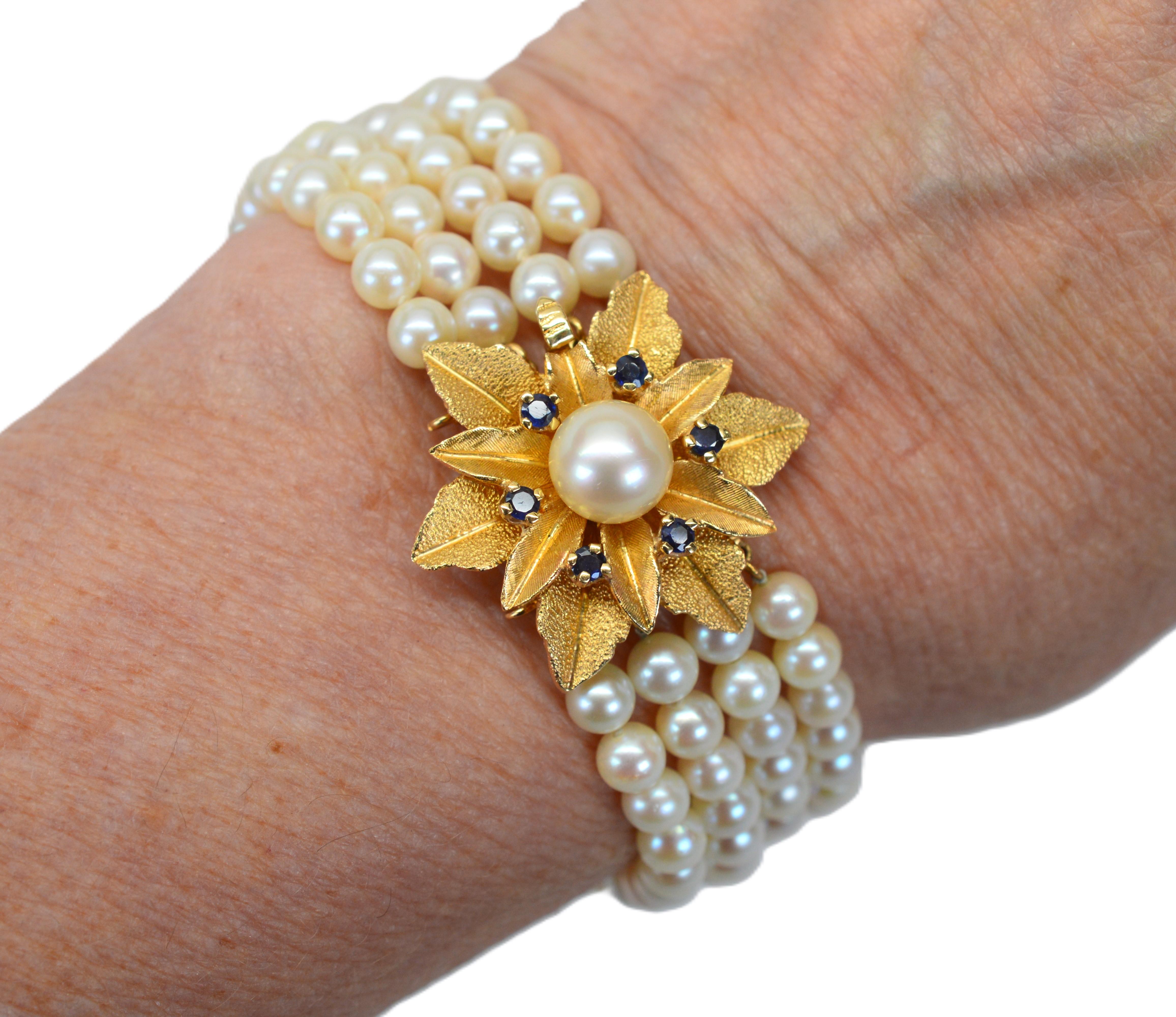 1950's Style Fünf Strang Perlenarmband mit Funktion 14 Karat Gold & Saphir Floral Burst Clasp. Hergestellt aus über hundert 5 1/2 mm feinen echten AAA Akoya-Perlen, blüht dieses fein konstruierte 7-Zoll-Armband mit Persönlichkeit mit einer großen