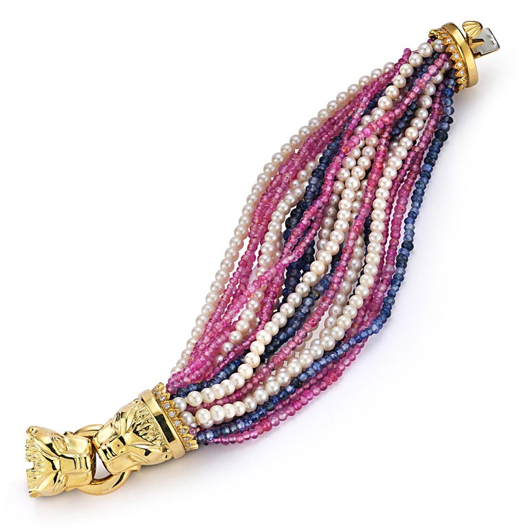 Multi Strand Pearl, Ruby & sapphire Lion Head Bracelet 

5 strands of pearls , 5 stands of rubies & 5 strands of sapphires attached to 18k gold lion head clasps 

Measurements: 9