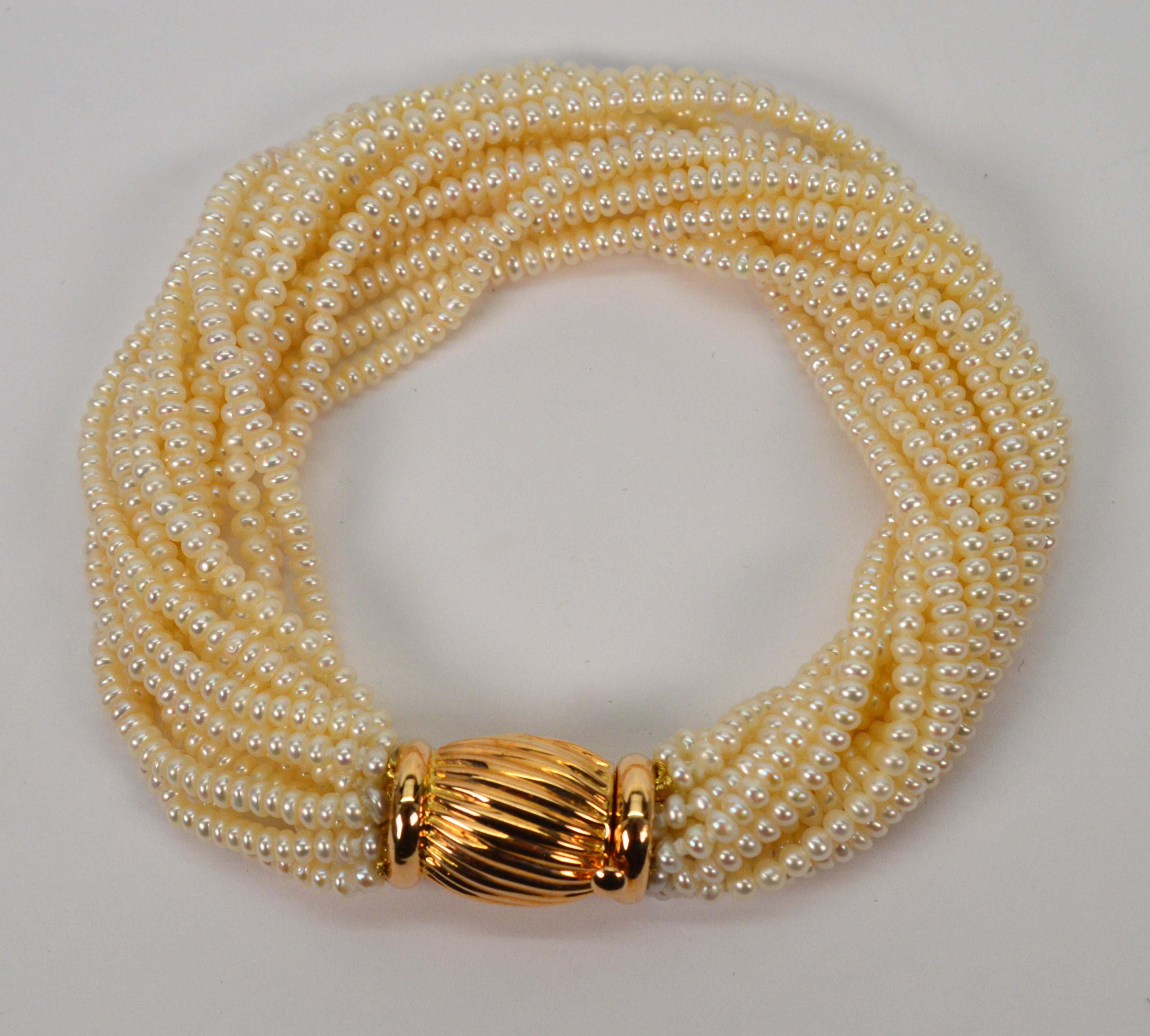 Enjoy a twist on a classic. Multiple strands of lustrous pearls accented with decorative  14 karat yellow gold bow tie clasp create this sophisticated pearl wrap bracelet. Expertly matched 2.8mm lustrous cultured off round pearls are hand strung