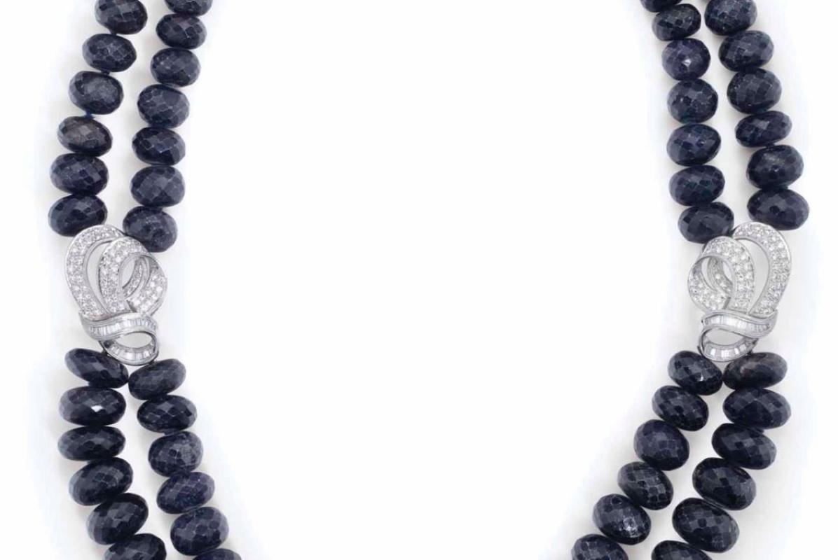 Questa collana presenta due file di zaffiri che si incontrano con un grappolo di diamanti, incastonati nel platino e chiusi da una chiusura in oro. Sulla collana c'è il timbro PT 900