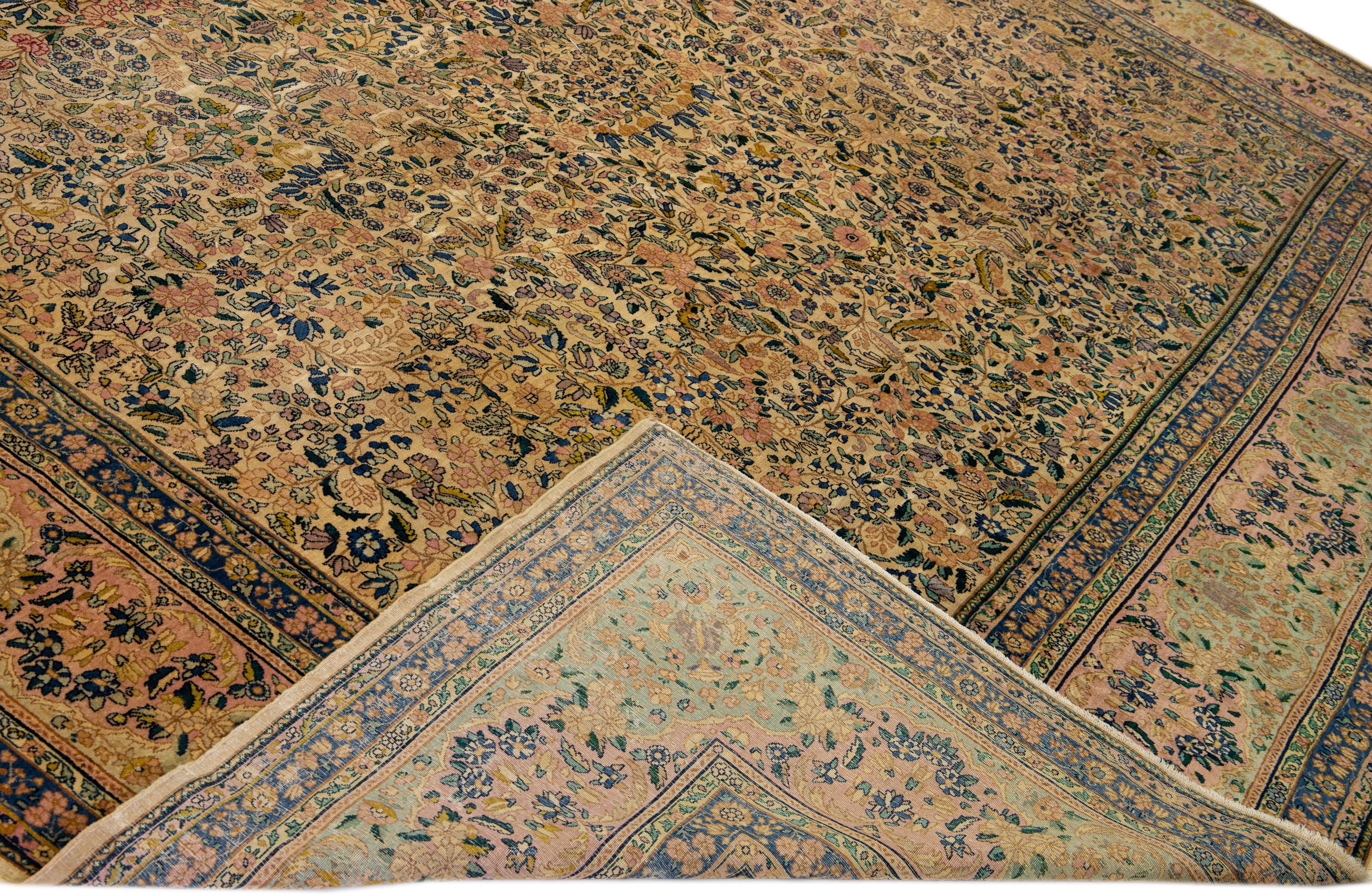 An extraordinary Beautiful antique Kirman hand-knotted wool rug with a tan field. This Persian rug has multicolor accents in a gorgeous garden floral design.

This rug measures: 11'4