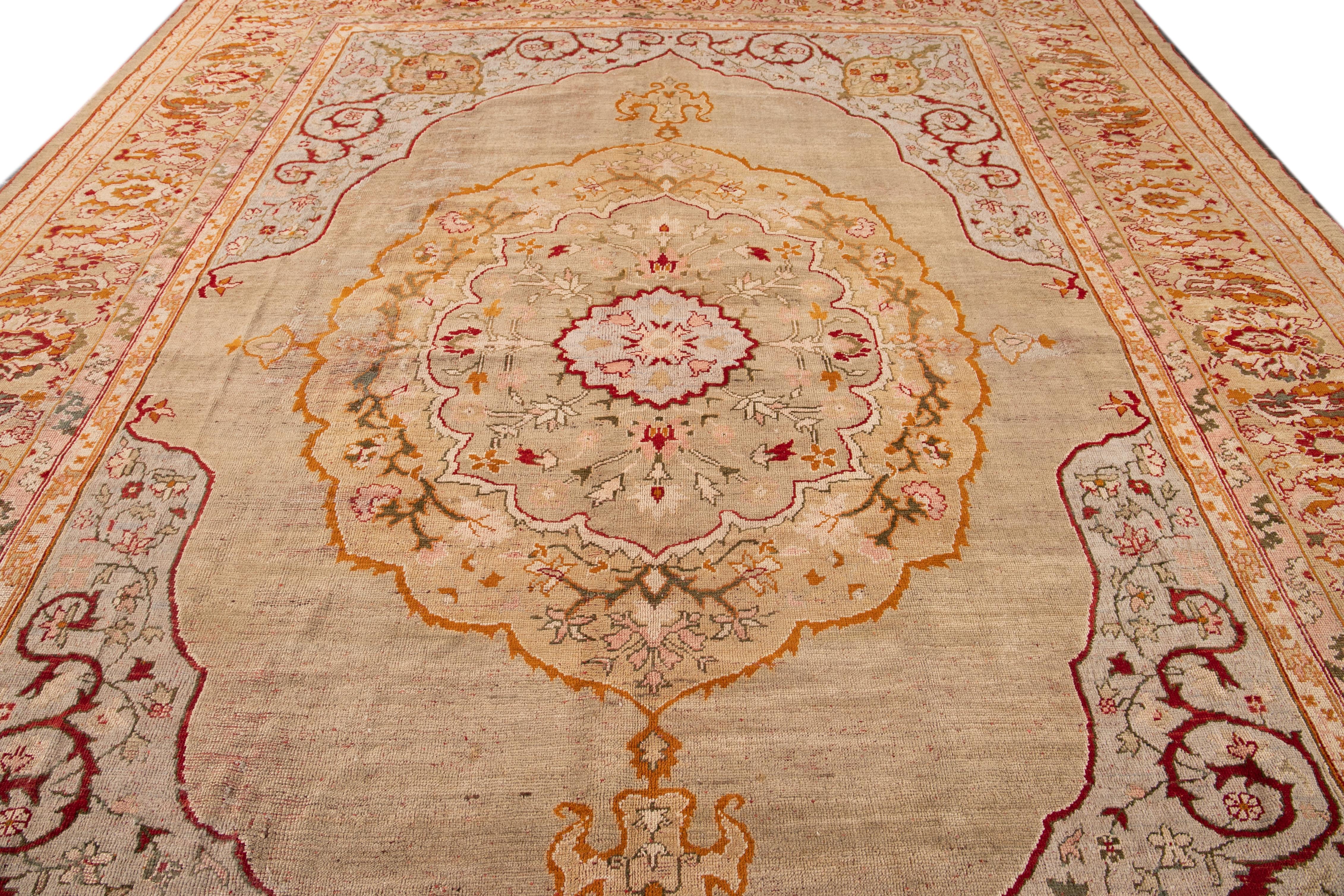 Beautiful Antique Turkish hand-knotted wool rug with a beige color field. This rug has a designed frame with pink, red, and gray accent colors in a gorgeous all-over medallion floral design.

This rug measures: 11'9