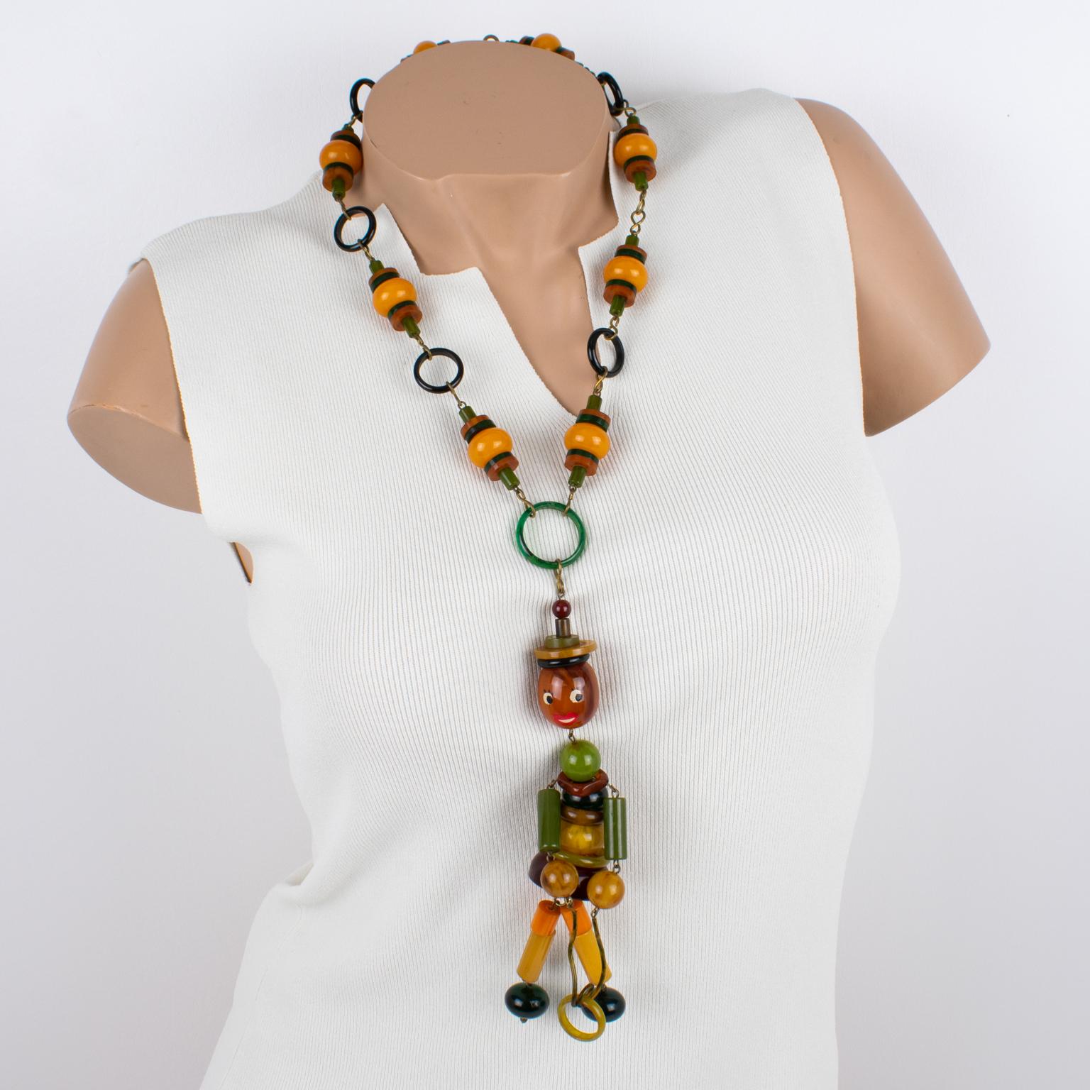This stunning rare Bakelite long necklace was hand-crafted in France in the 1940s. The piece features a beaded design with an articulated crib toy doll pendant. The beaded necklace boasts autumnal colors with a lovely, warm palette of yellow