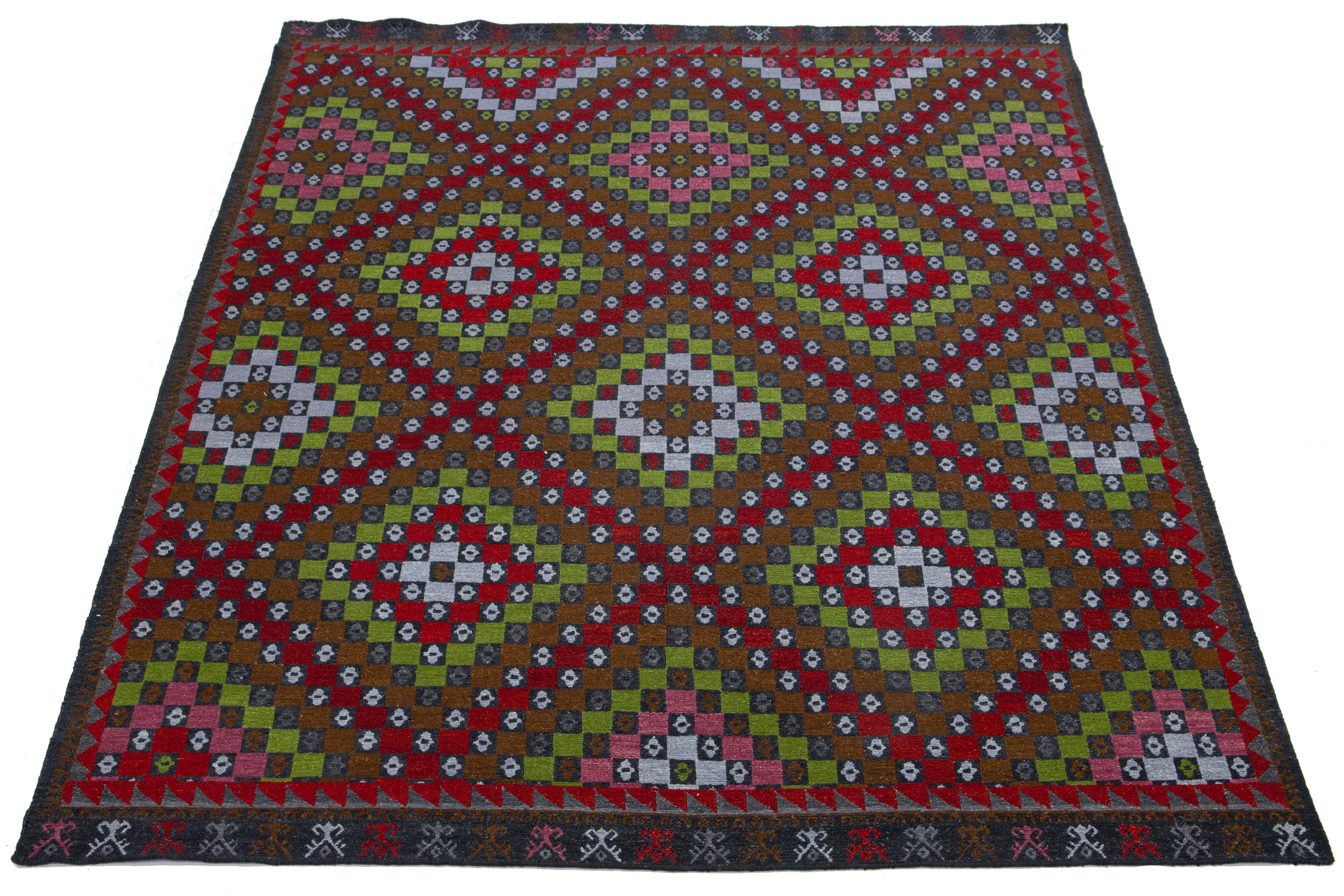 Questo bellissimo tappeto moderno in lana Soumak annodato a mano ha un campo grigio scuro. Presenta accenti verdi, marroni e rossi in uno splendido disegno geometrico all-over.

Questo tappeto misura 9' x 12'.

I nostri tappeti vengono puliti