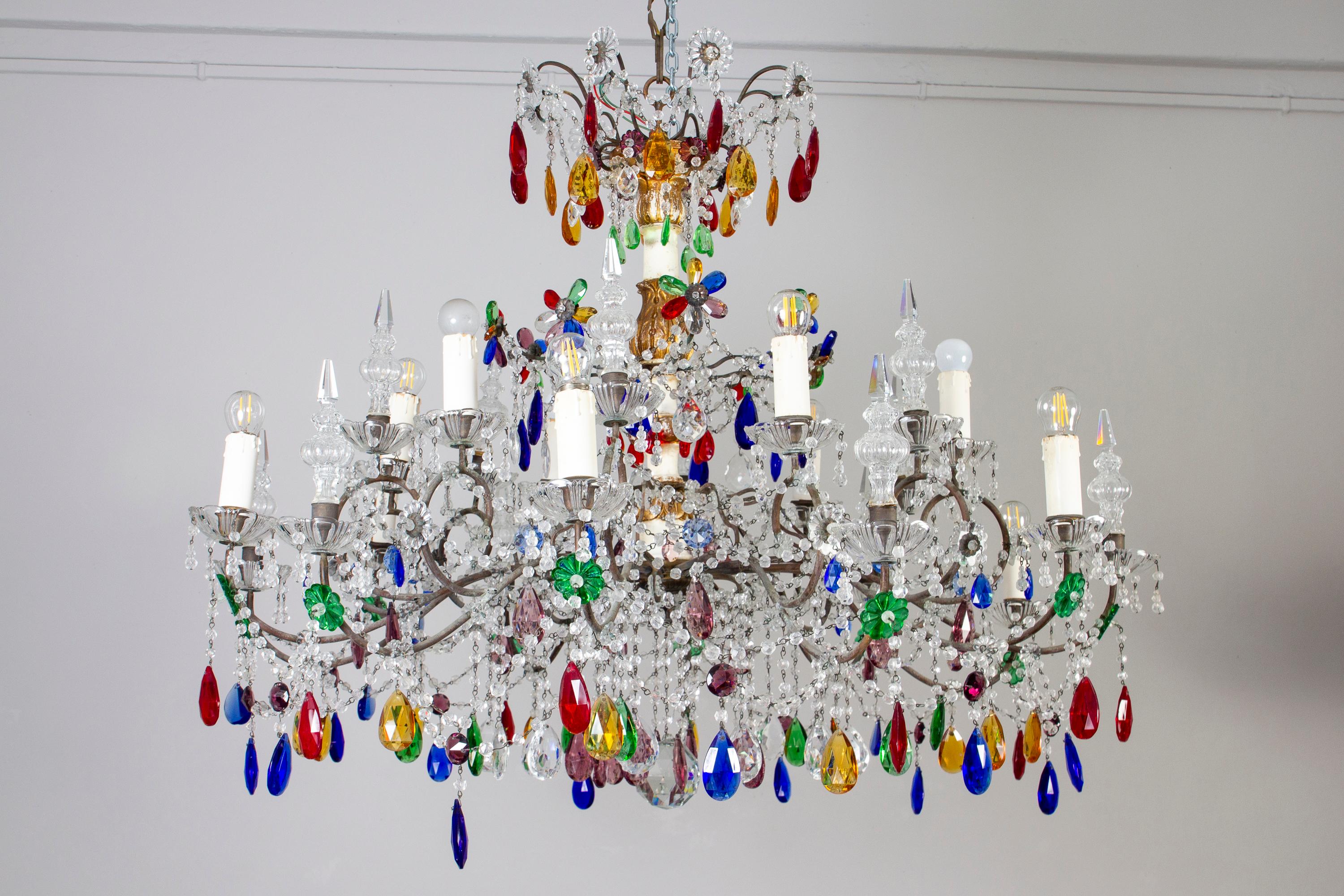 Incredibile  lampadario in cristallo multicolore a 12 luci.  Base centrale in legno dorato finemente intagliato con 12 
