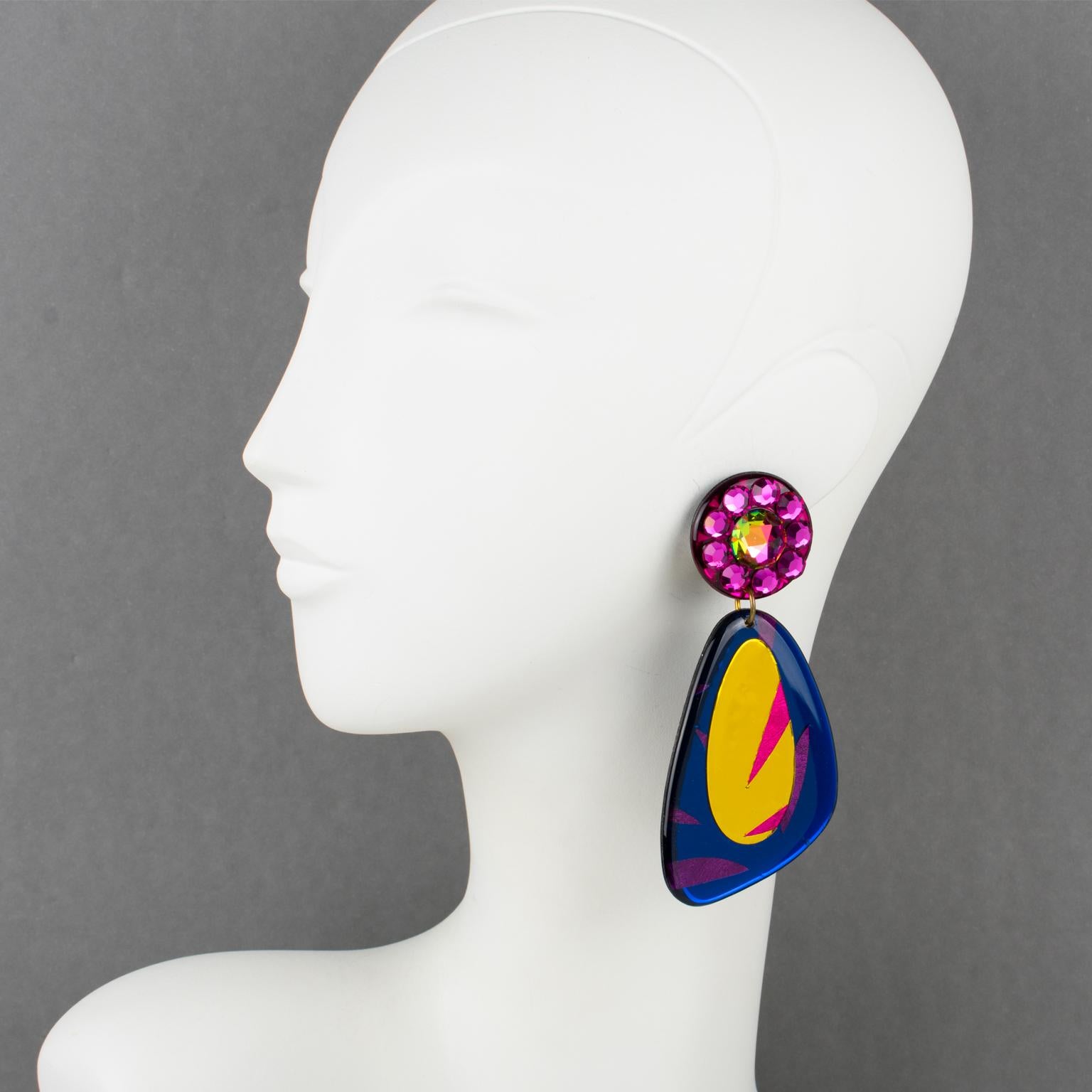 These stunning Italian designer studio Lucite dangling clip-on earrings feature a chandelier shape with geometric design in navy blue, gold, and hot pink colors with a mirror texture effect. The clip fittings are paved with hot pink and hyacinth AB