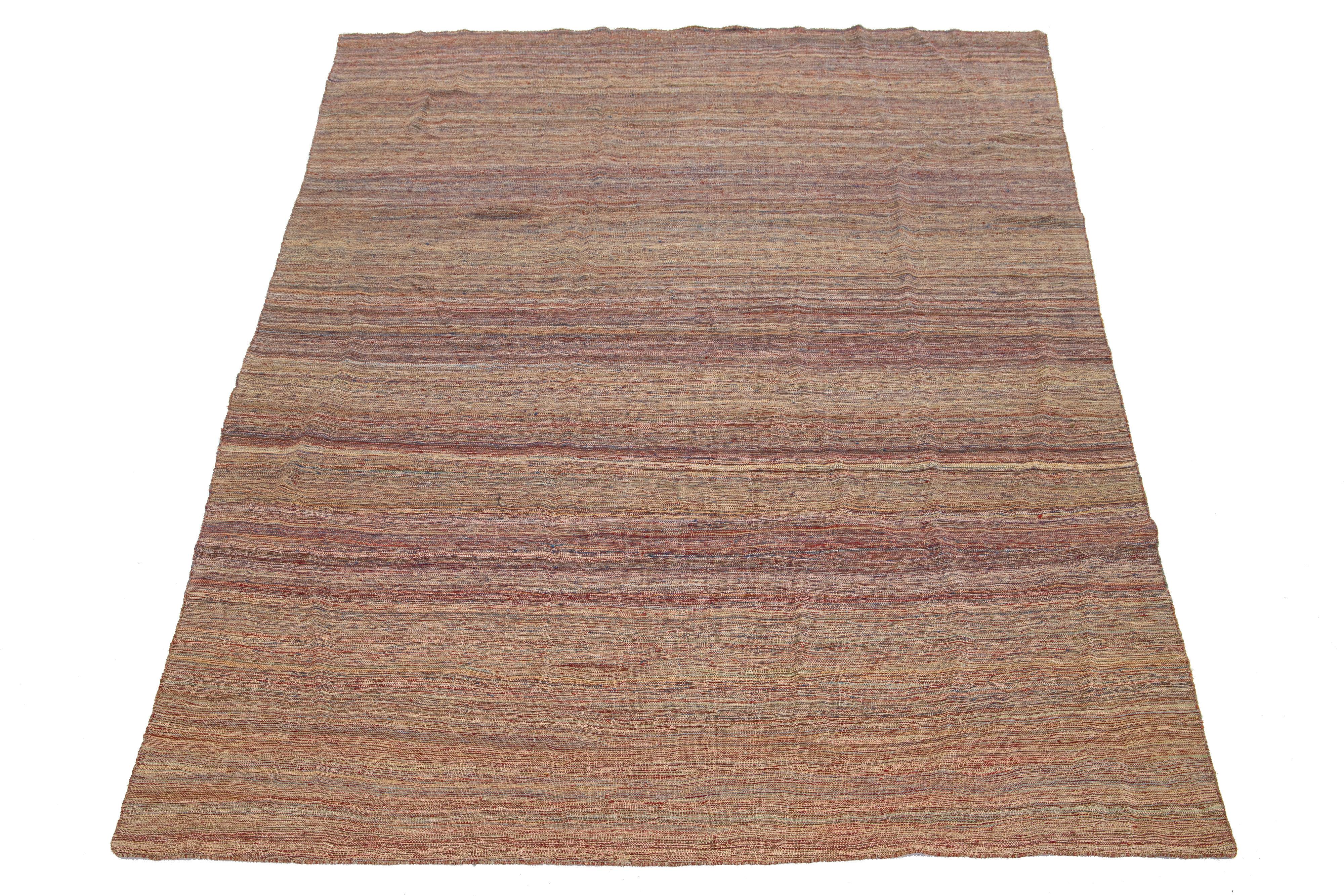 Dieser Teppich zeigt ein modernes Kilim-Flachgewebedesign aus Wolle mit einem Streifenmuster auf einem Grund in Rot, Blau und Beige.

Dieser Teppich misst 7'6