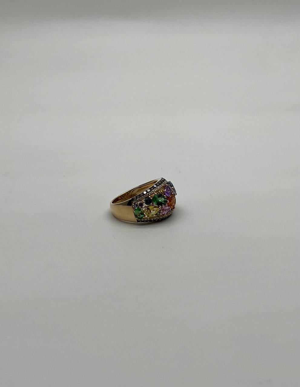 Questo pezzo accattivante presenta una serie dinamica di zaffiri multicolori, ognuno dei quali incastonato meticolosamente per creare un vivace mosaico di colori. La superficie dell'anello è impreziosita da un'armoniosa miscela di pietre verdi,