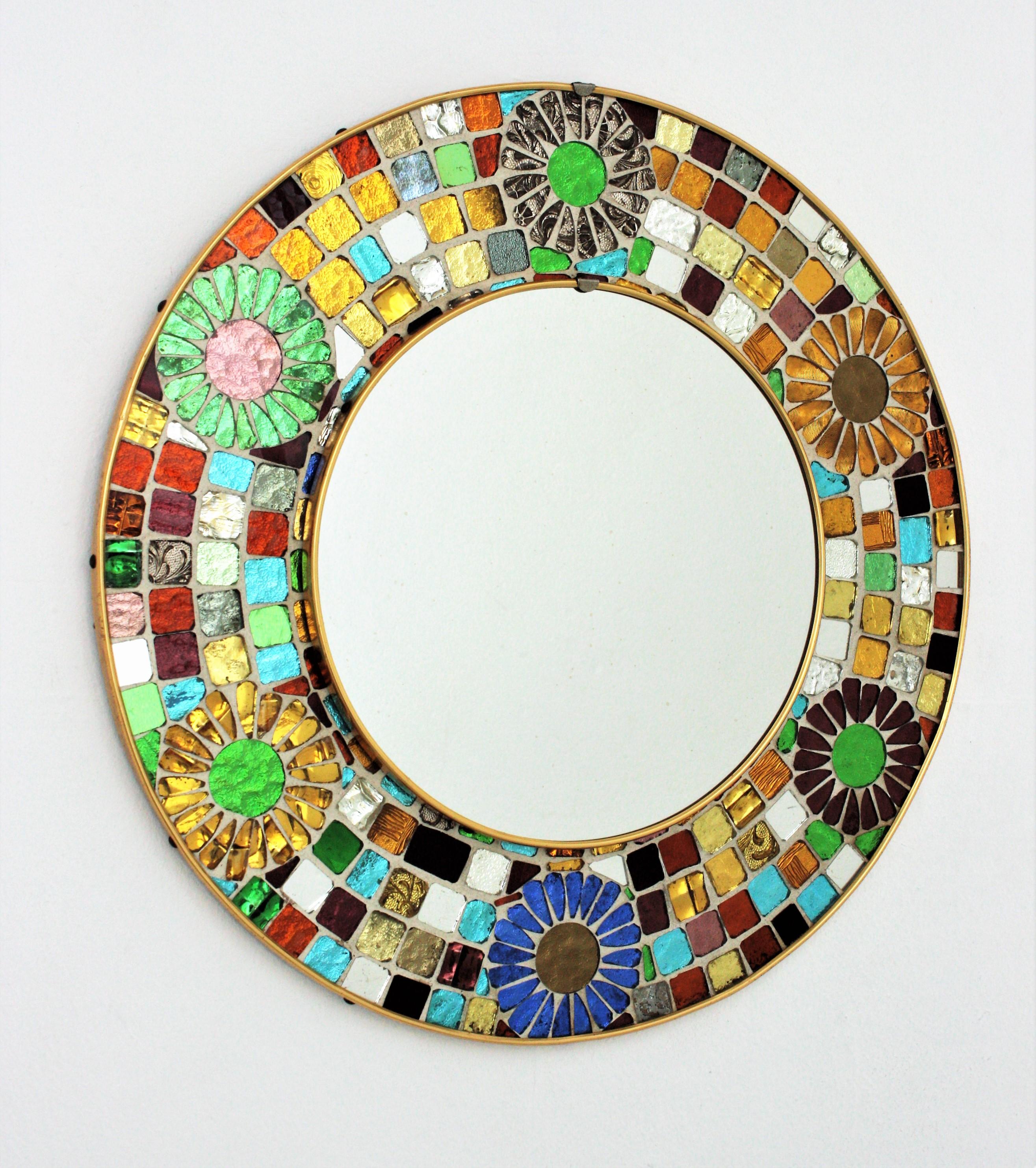 One of a kind Mid-Century Modern round colorful glass mosaic mirror with decorative flower details. Spain, 1960s.
This eye-catching mirror features a central round glass surrounded by a colorful mosaic frame made of hand-cut small pieces of glass in