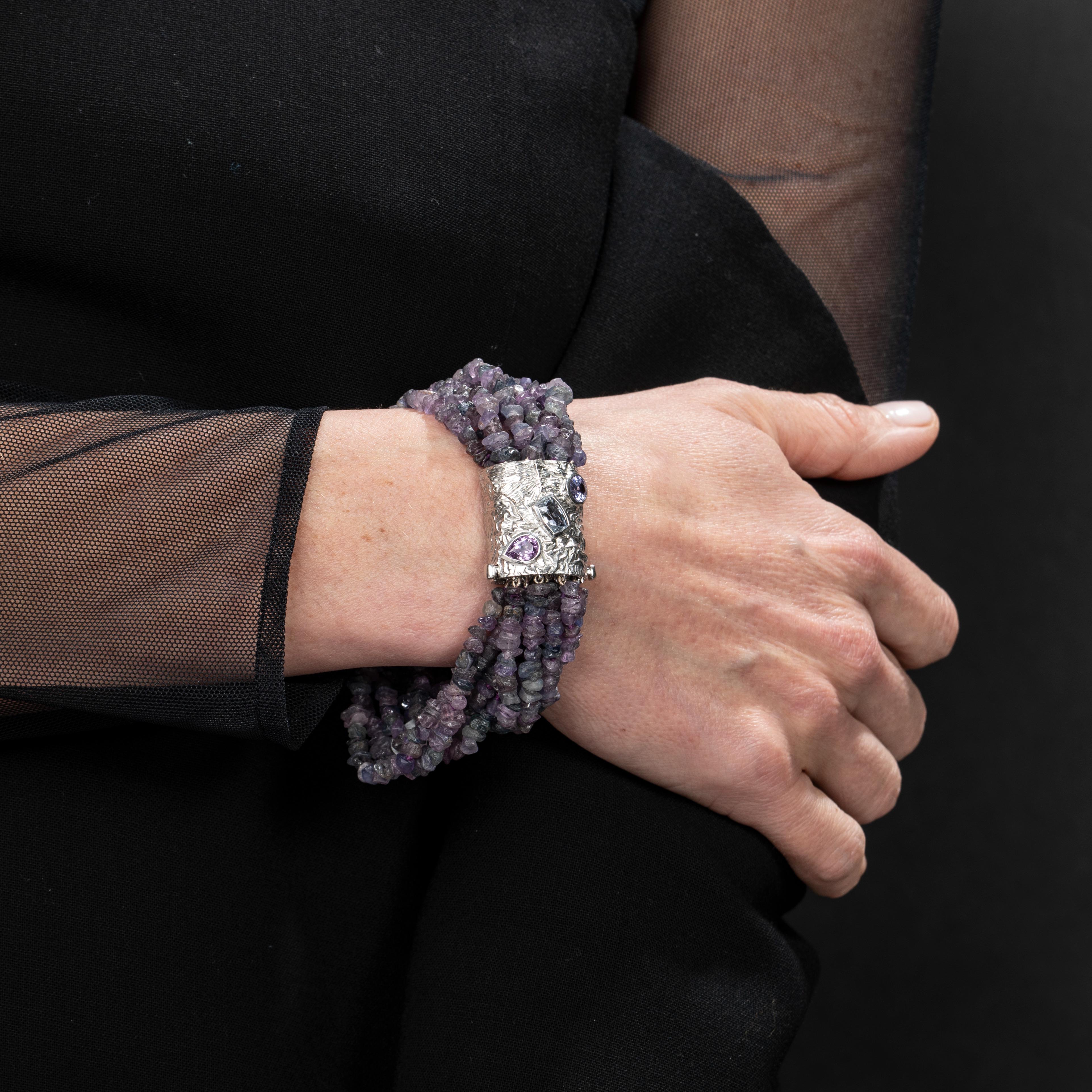 This one of a kind creation is like a bouquet for your wrist - comprised of rough natural mixed colour sapphire beads in various hues of purple and violet, this bracelet is brought together by a reticulated 18k white gold band with bezel set