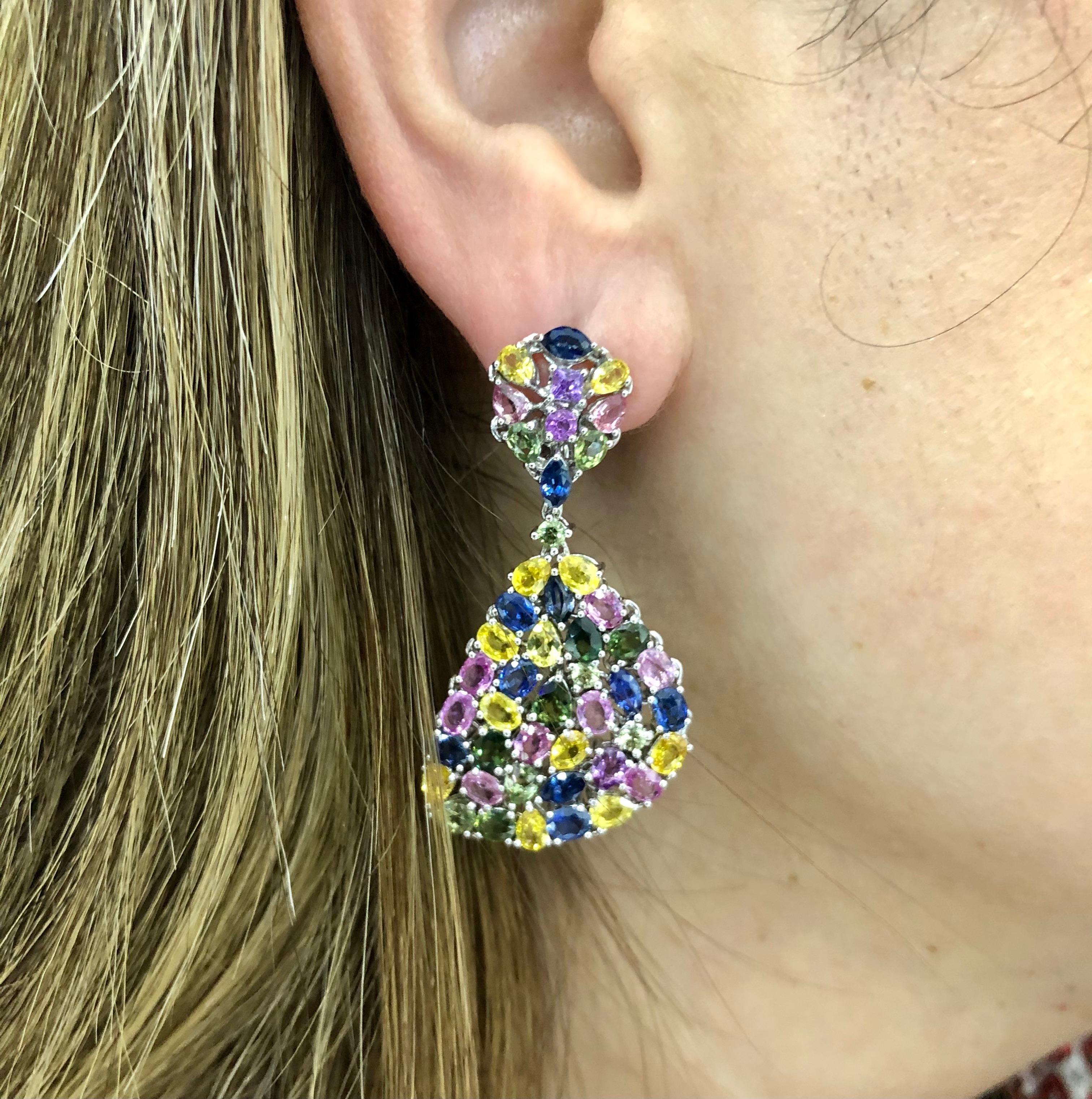 Gorgeous one of a kind earrings crafted in 18k white gold. Fantastic pair that pops with color. The earrings are set with multiple natural colored Sapphire gemstones throughout.  Yellow, blue, green, pink and purple colored Sapphires adorn the pair