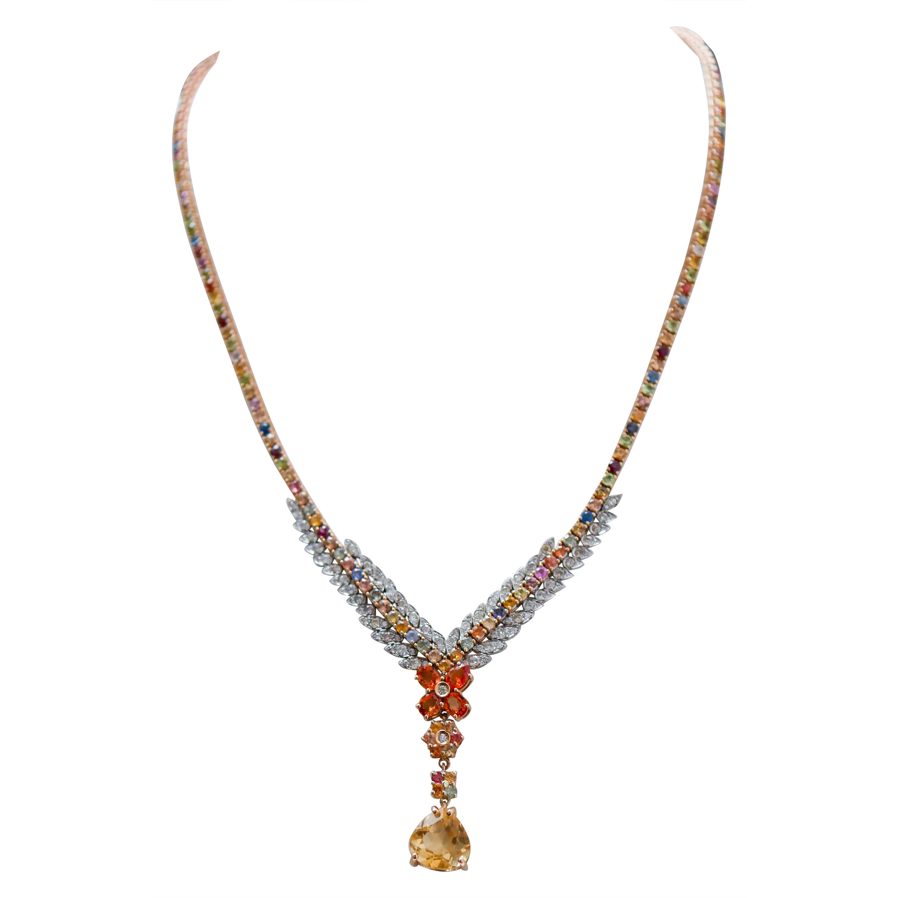Elegante collar tenis en estructura de oro rosa de 14 kt montado con zafiros multicolores, topacios, peridotos, granates y iolita en toda la longitud. En la parte final, lateralmente, hojas en oro blanco tachonadas con diamantes y, como colgante,
