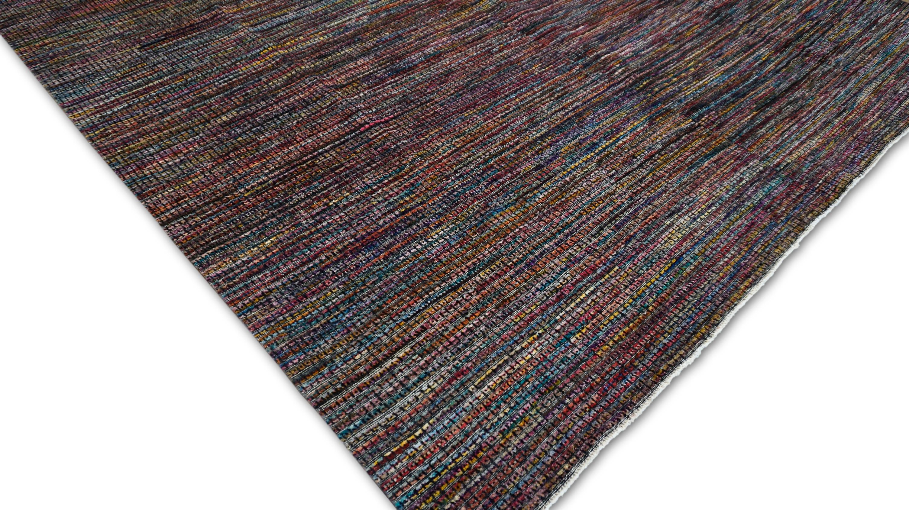 Dieser handgeknüpfte Wollteppich ist ein Meisterwerk der Textur- und Farbmischung und bietet eine lebendige, vielfarbige Palette, die in ein subtiles, organisches Muster eingewoben ist. Mit einer harmonischen Verschmelzung von erdigen Rottönen und