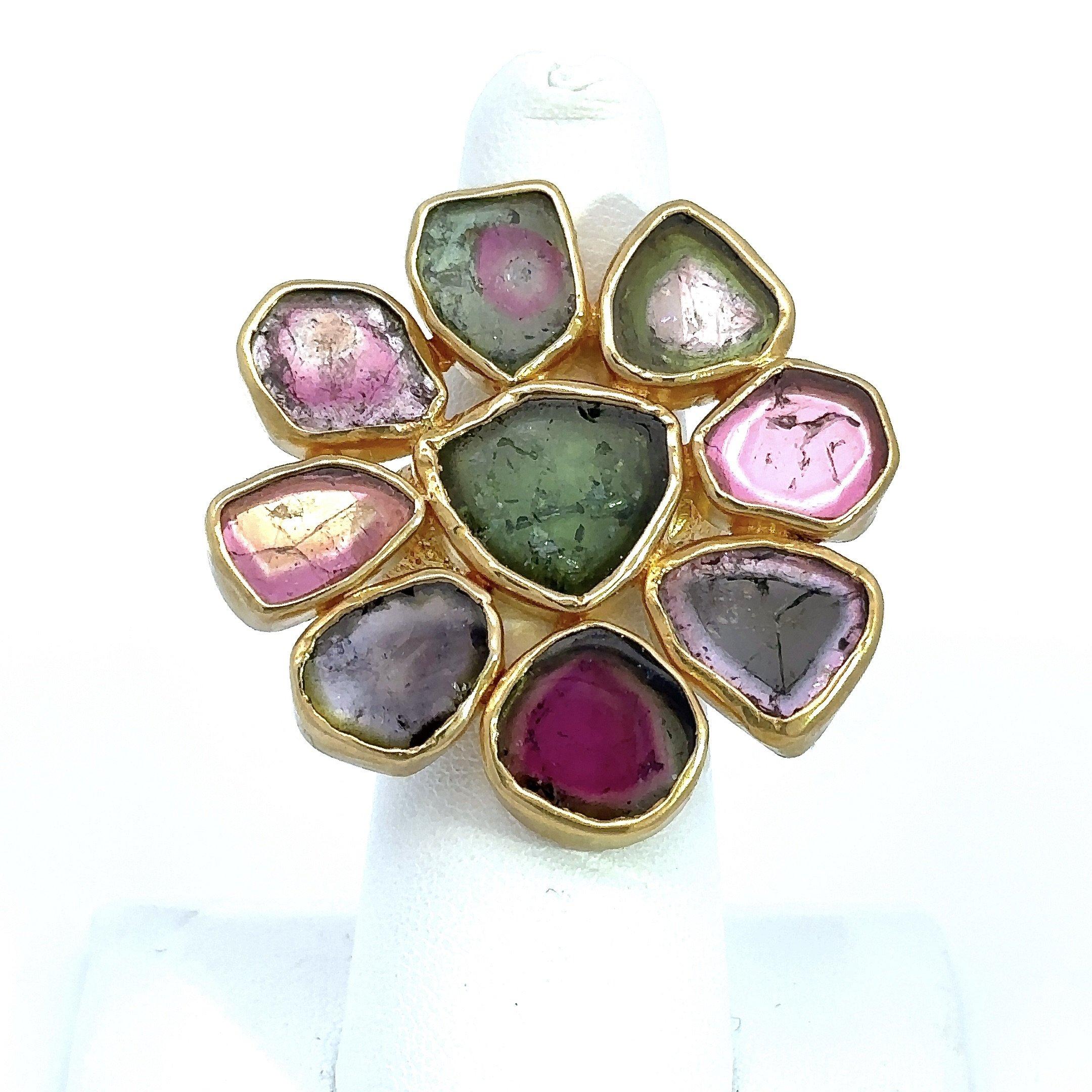 This striking floral design cocktail ring features a burst of vibrant shades of green, pink, purple and watermelon tourmaline, bezel-set in a rich 21K yellow gold. The top of the ring measures approximately 1.5” inches x 1.5” inches and the shank