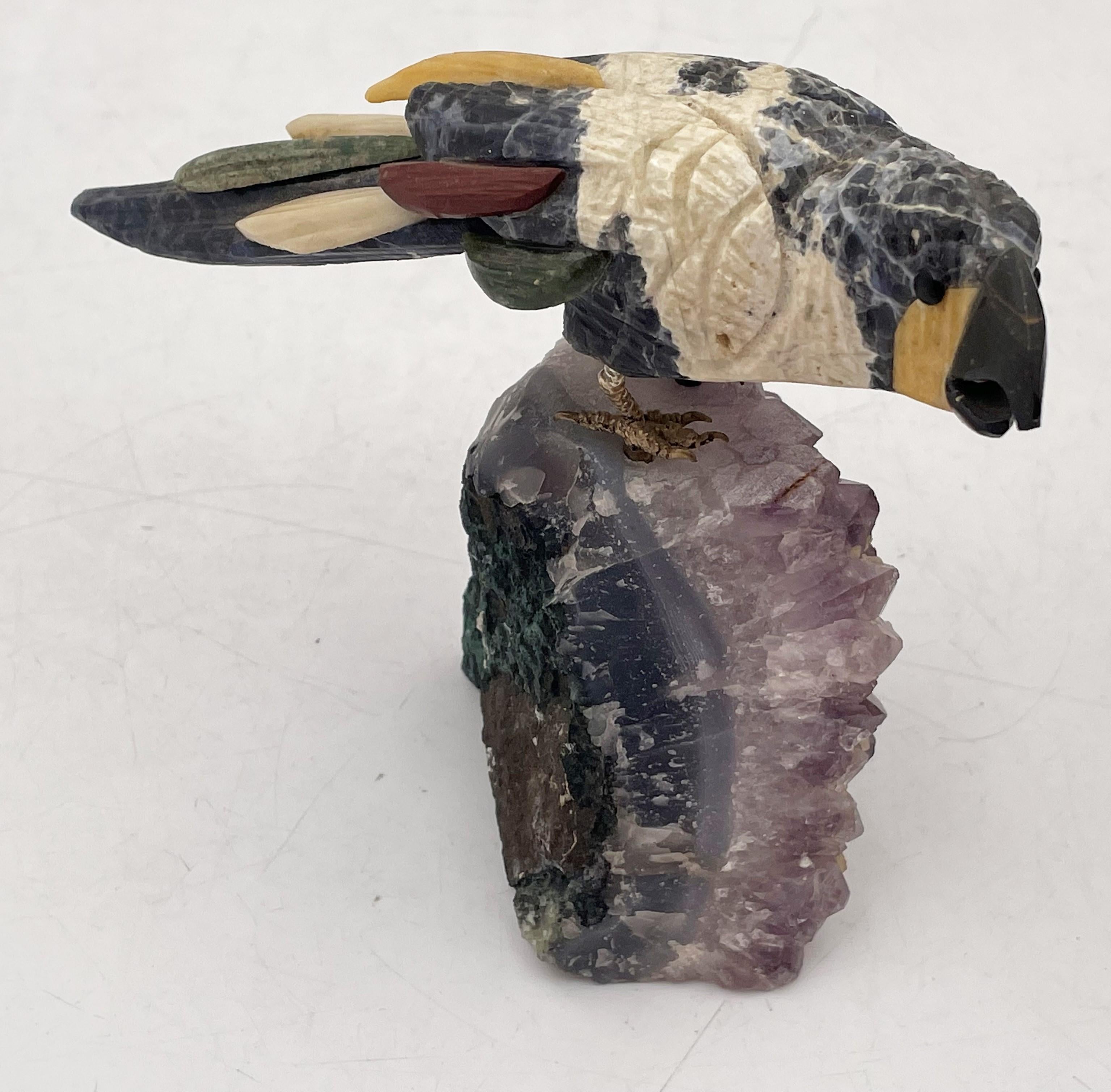 Sehr realistische und detaillierte Skulptur eines mehrfarbigen Vogels mit vergoldeten Silberbeinen, der auf einem amethystfarbenen Sockel sitzt. Dieses schöne Stück misst 3 3/4'' in der Höhe, 5 3/8'' in der Tiefe und 2 1/2'' in der Breite.

Bitte