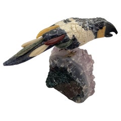 Escultura de piedra tallada de pájaro multicolor sobre amatista