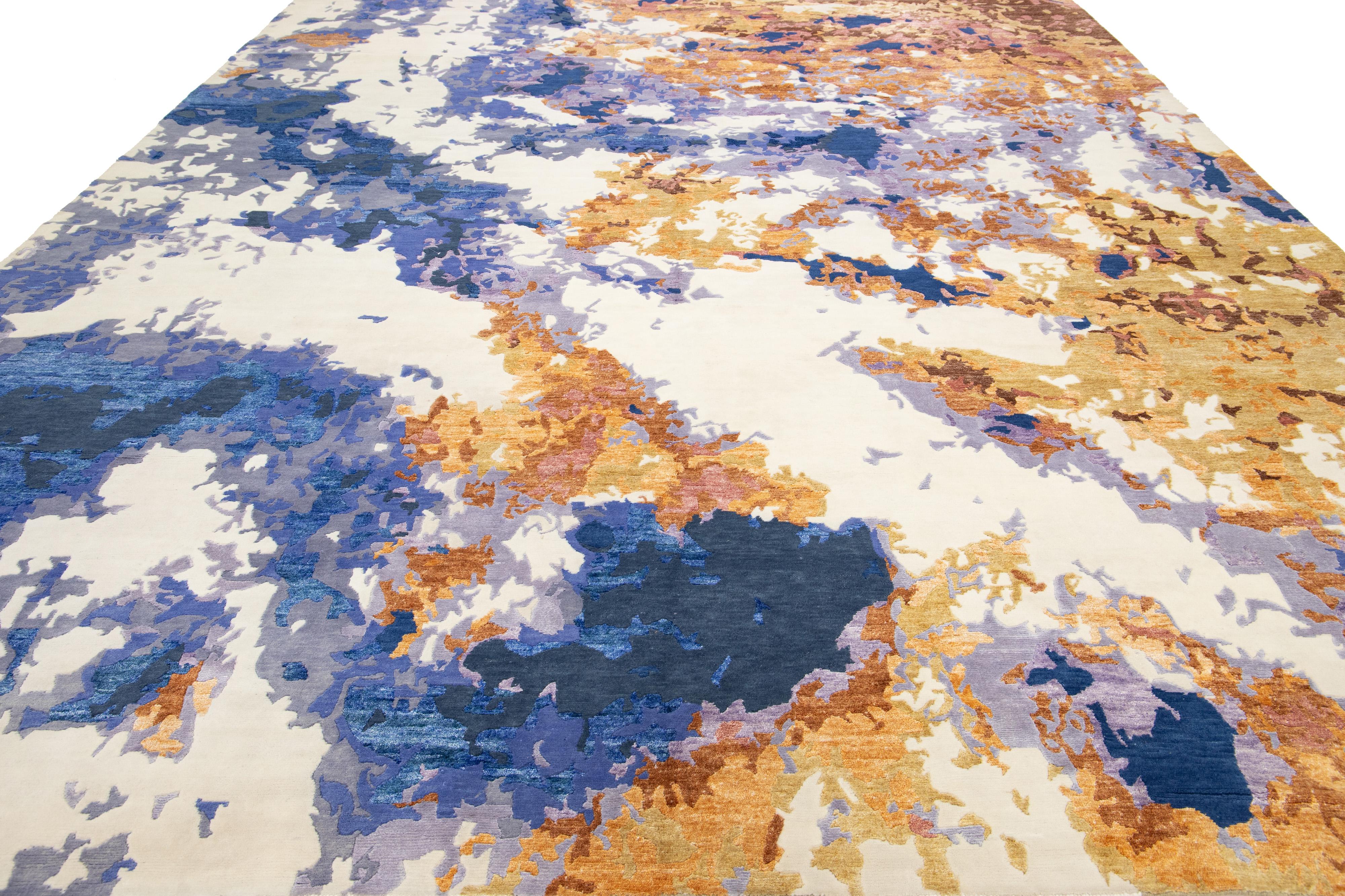 Ce tapis contemporain noué à la main présente un design abstrait saisissant dans des couleurs vibrantes qui attire l'attention sans effort. Fabriqué en laine ou en soie de haute qualité, il arbore une élégante toile de fond ivoire, bleue, violette