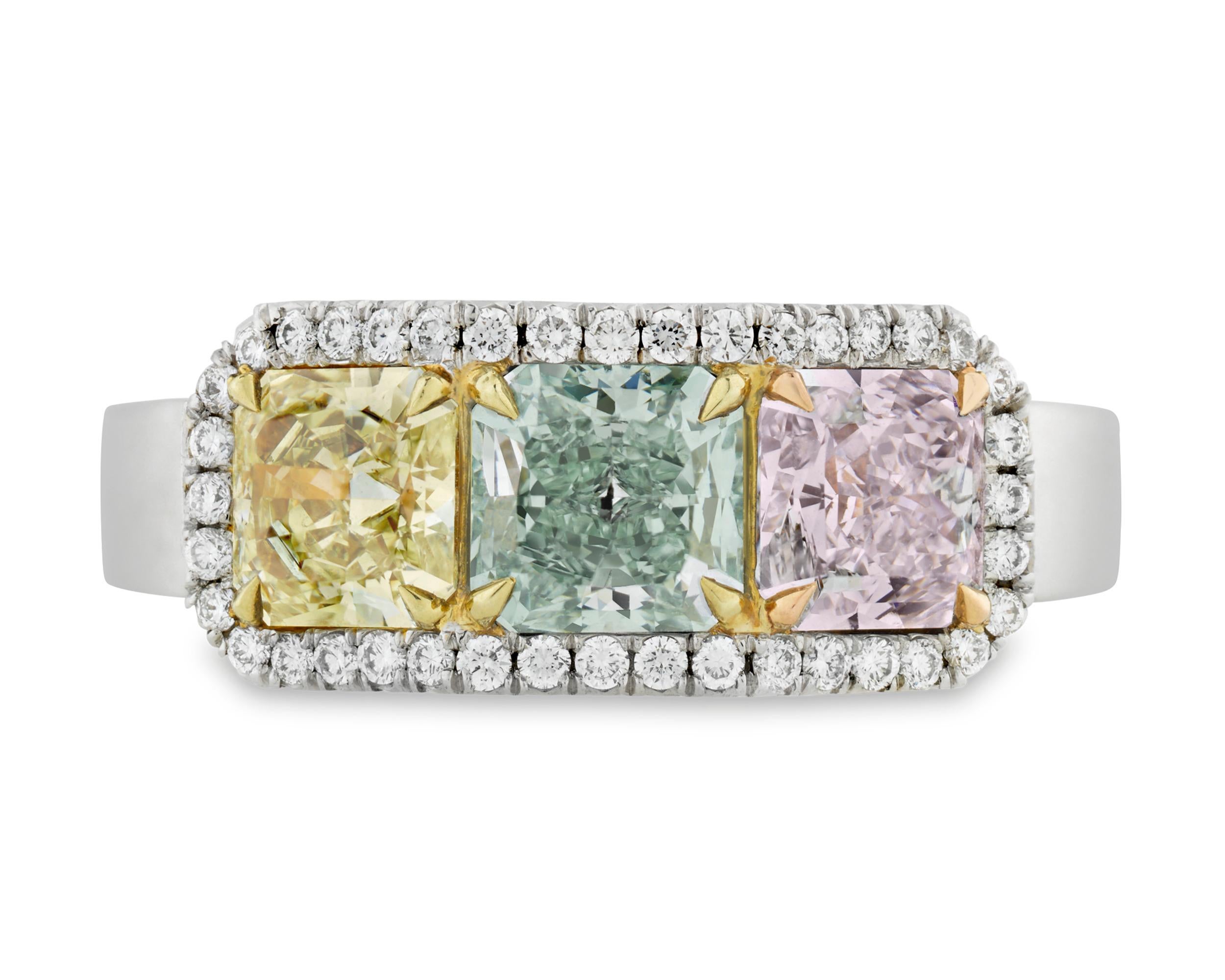 This one-of-a-kind ring is set with not one, but three immensely rare colored diamonds. To the left is a brilliant fancy light yellow diamond weighing 0.70 carat and to the right is a delicate 0.76-carat very light pink diamond that is also