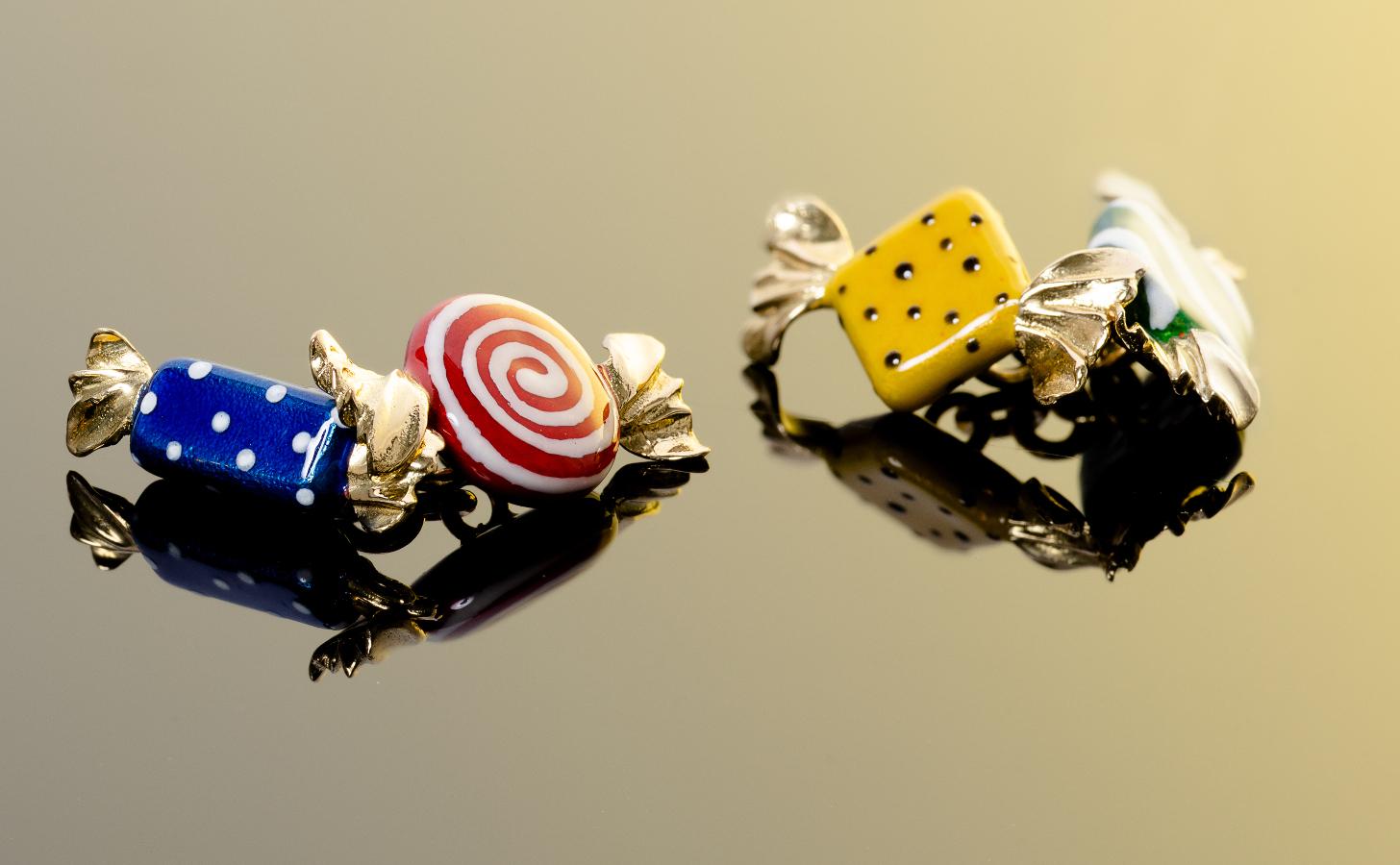  Paire de boutons de manchette en forme de bonbons emballés, appliqués d'émail translucide rouge, bleu, blanc et vert. 

Connexions en maillons de chaîne dorés.   

Monté en or jaune 18Kt