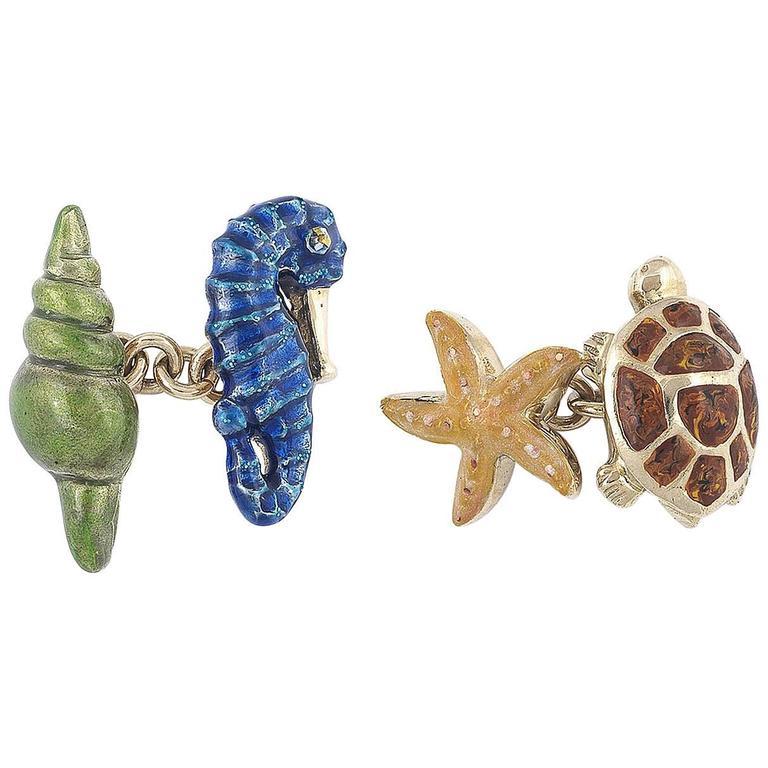 Par de gemelos con diseño de concha, caballito de mar, estrella de mar y tortuga marina aplicados con esmalte translúcido amarillo, azul, marrón y verde. 

Conexiones de eslabones de cadena de oro.   

Montado en oro amarillo de 18 quilates