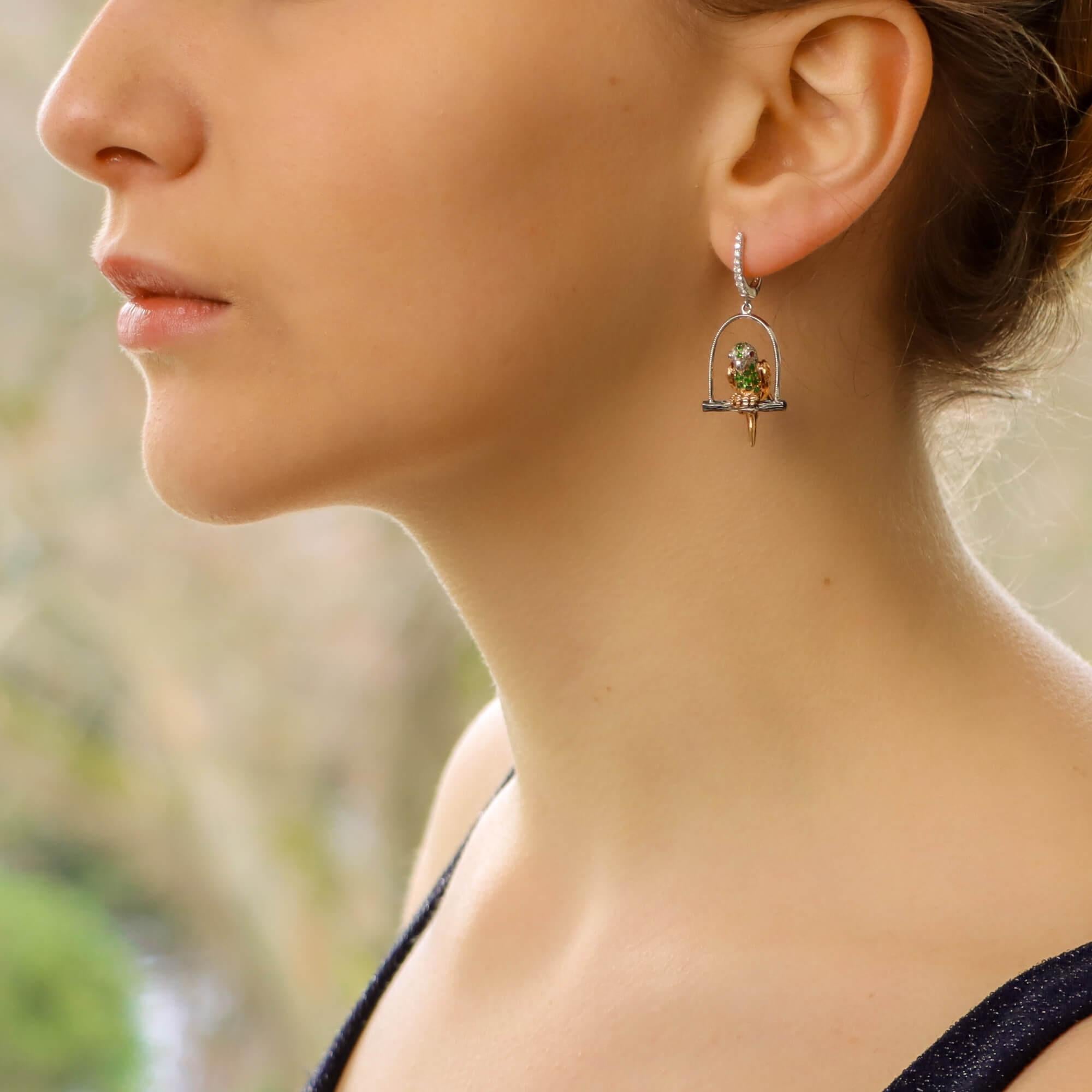 A beautiful pair of modern parrot earrings set on 18k white gold.

Each parrot is perched on a white gold swing roost and is grain set with round blue, pink, orange and yellow sapphires, rubies, tsavorite garnets and diamonds across its body, wings