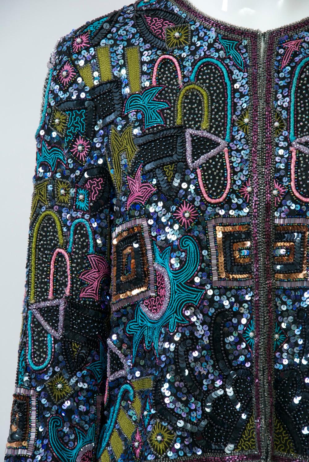 A profusion of multicolored beads and sequins adorns the surface of this eye-catching evening jacket.  The mostly pastel beads cover the entire black silk surface in a riotous pattern predominated by narrow arcs and interpersed with some floral and