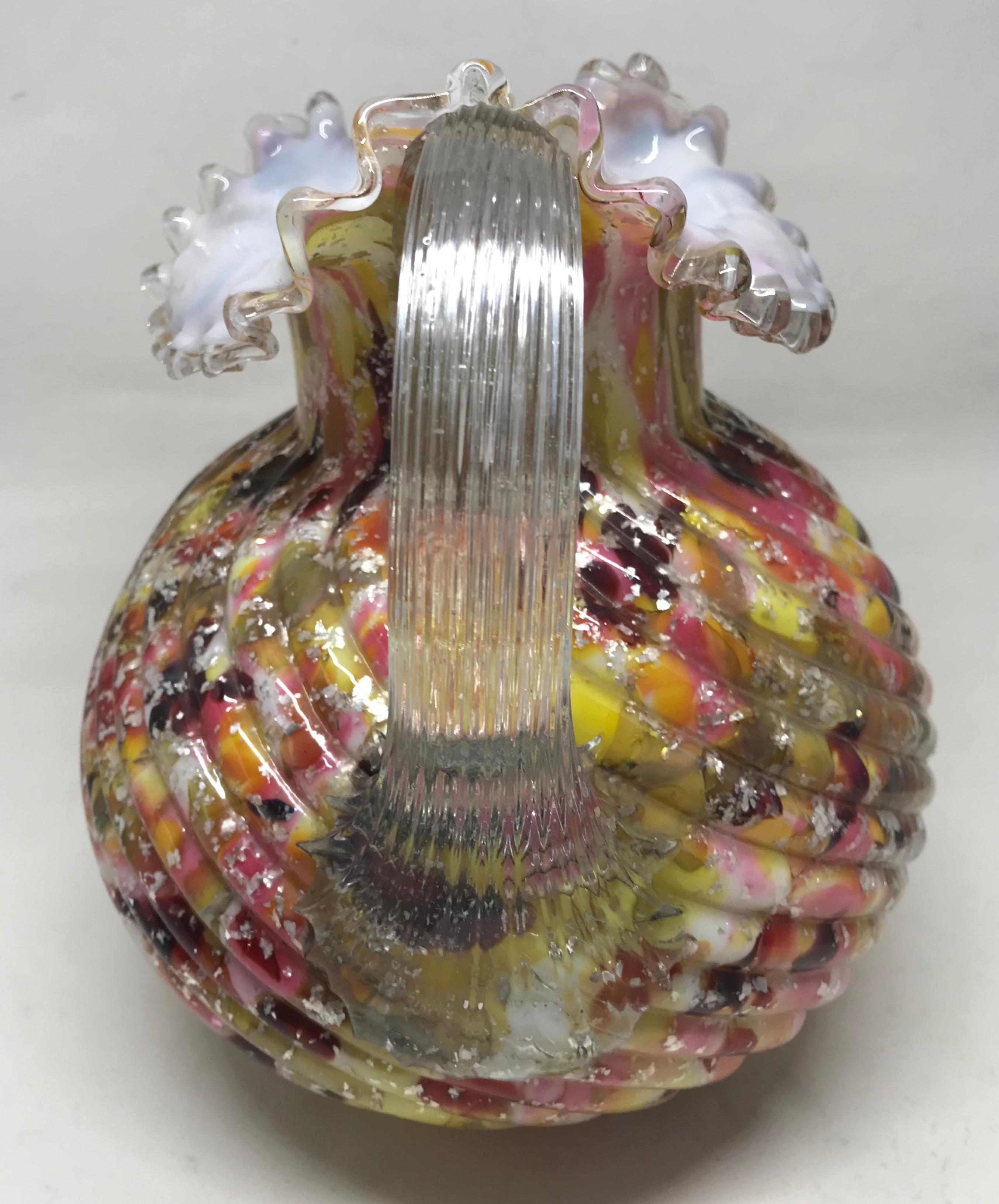 Multicolored glass pitcher. American hand blown pink, yellow, amber and silver fused glass design pitcher with ruffled spout and rim and clear glass handle. United States, circa 1900.
Dimensions: Handle to spout 7