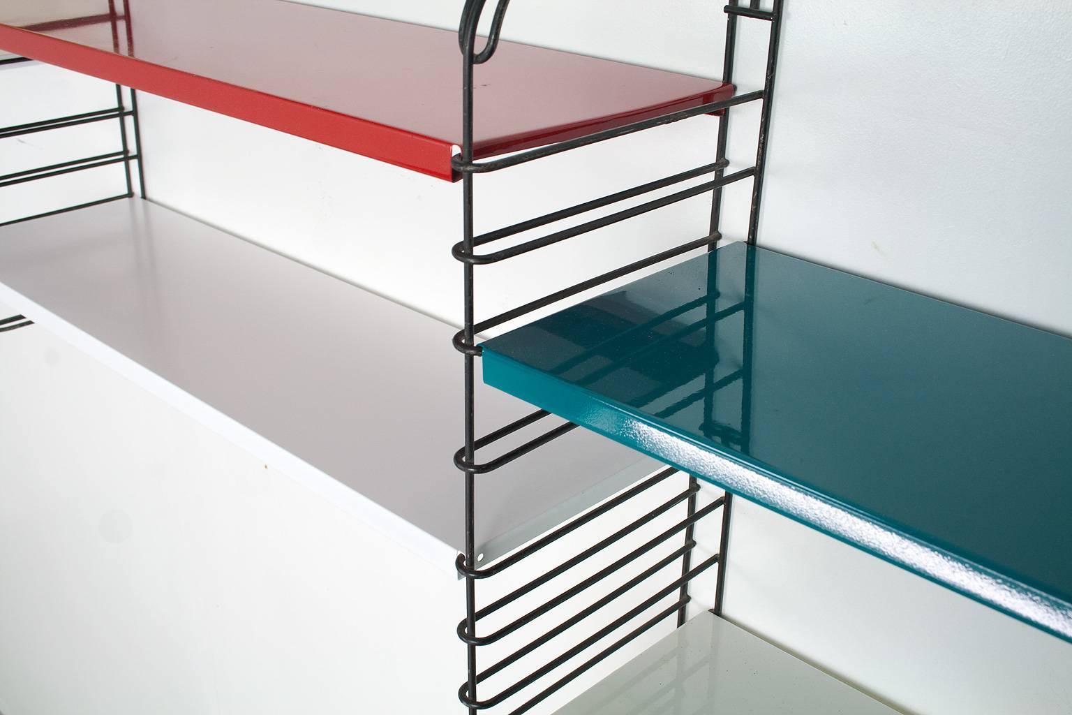 Beautiful industrial, modular wall unit with four black uprights and eight metal shelves in the colors white, red, yellow and teal. 

The colored shelves have been completely professionally restored with a satin gloss metal lacquer. The white