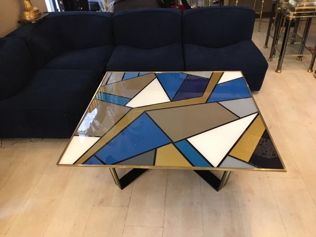 Multicolored opalines glass square Italian coffee table with a brass edge. 
The multicolored opalines create a geometric design in the style of Mondrian. 
The cross legs are in black metal with brass detail.