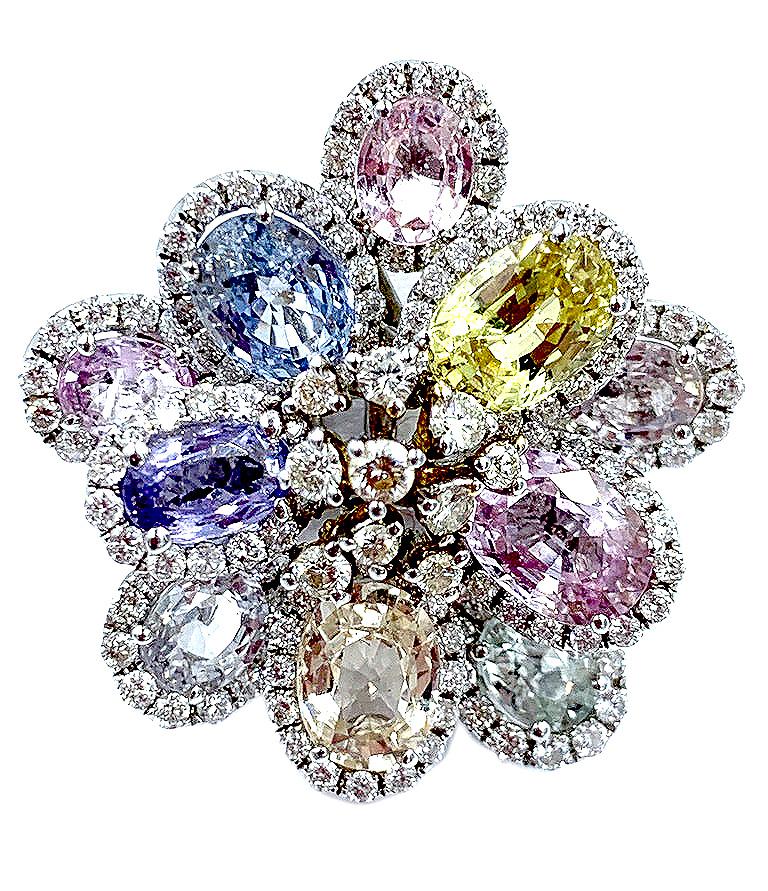 
Beautiful multicolored pastel sapphires in 7.65cts and  0.29ct carats of diamonds make up this incredibly beautiful flower ring. Each oval cut sapphire is mounted within an oval frame of sparkling white diamonds. The unique design and quality