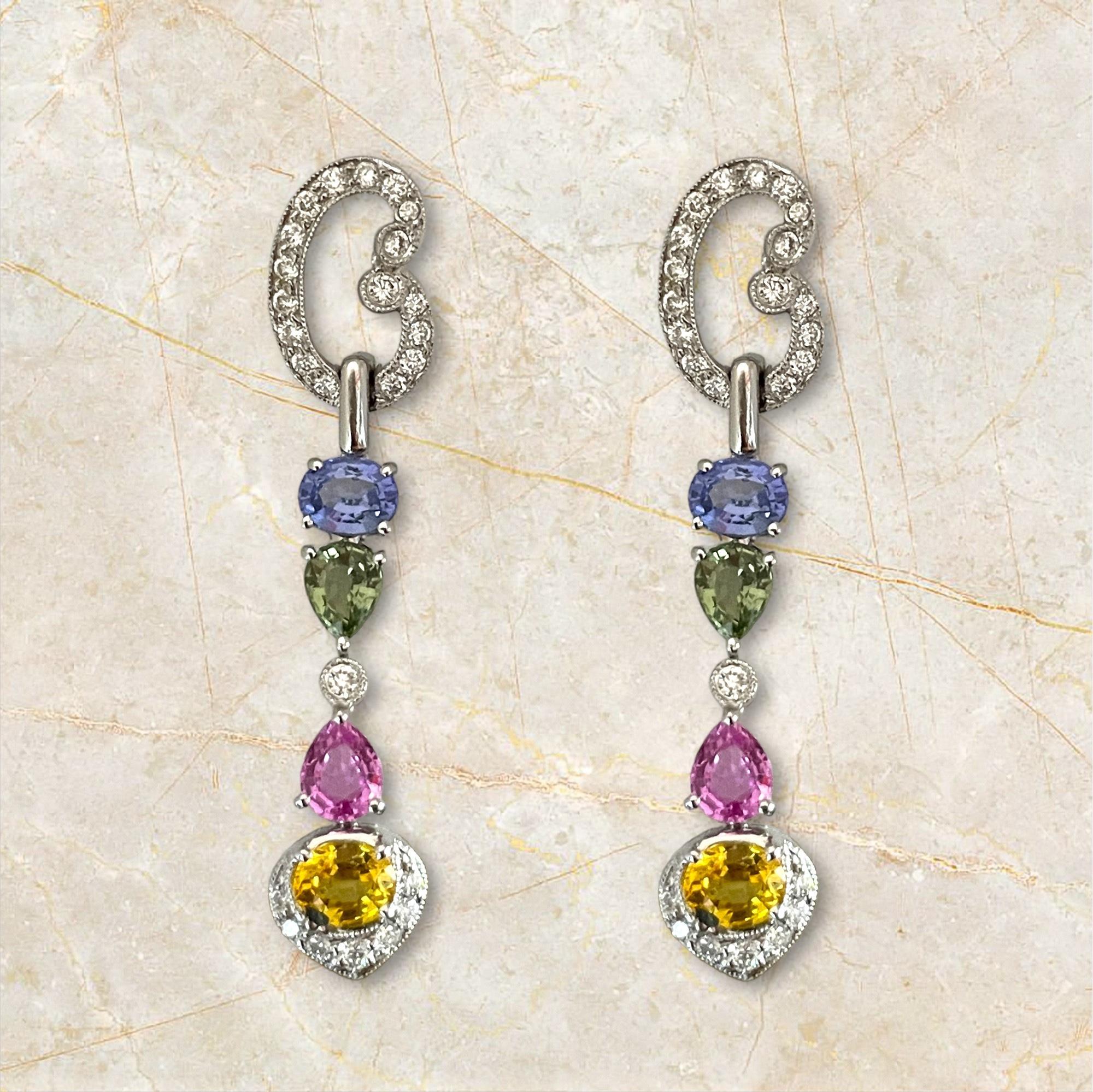 Estos impresionantes pendientes colgantes de oro blanco de 18 quilates presentan una cautivadora variedad de zafiros multicolores, bellamente complementados por brillantes diamantes. Cada pendiente muestra una paleta vibrante con formas de zafiro
