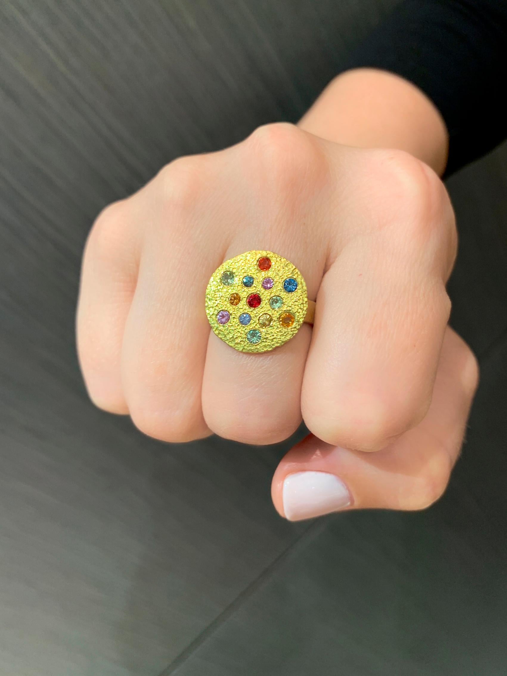 One of a Kind Lava Disc Ring handmade by acclaimed jewelry artist Petra Class featuring an assortment of shimmering, vibrant multicolored sapphires (blue, red, violet, orange, yellow, green, periwinkle, and teal), individually bezel-set in the