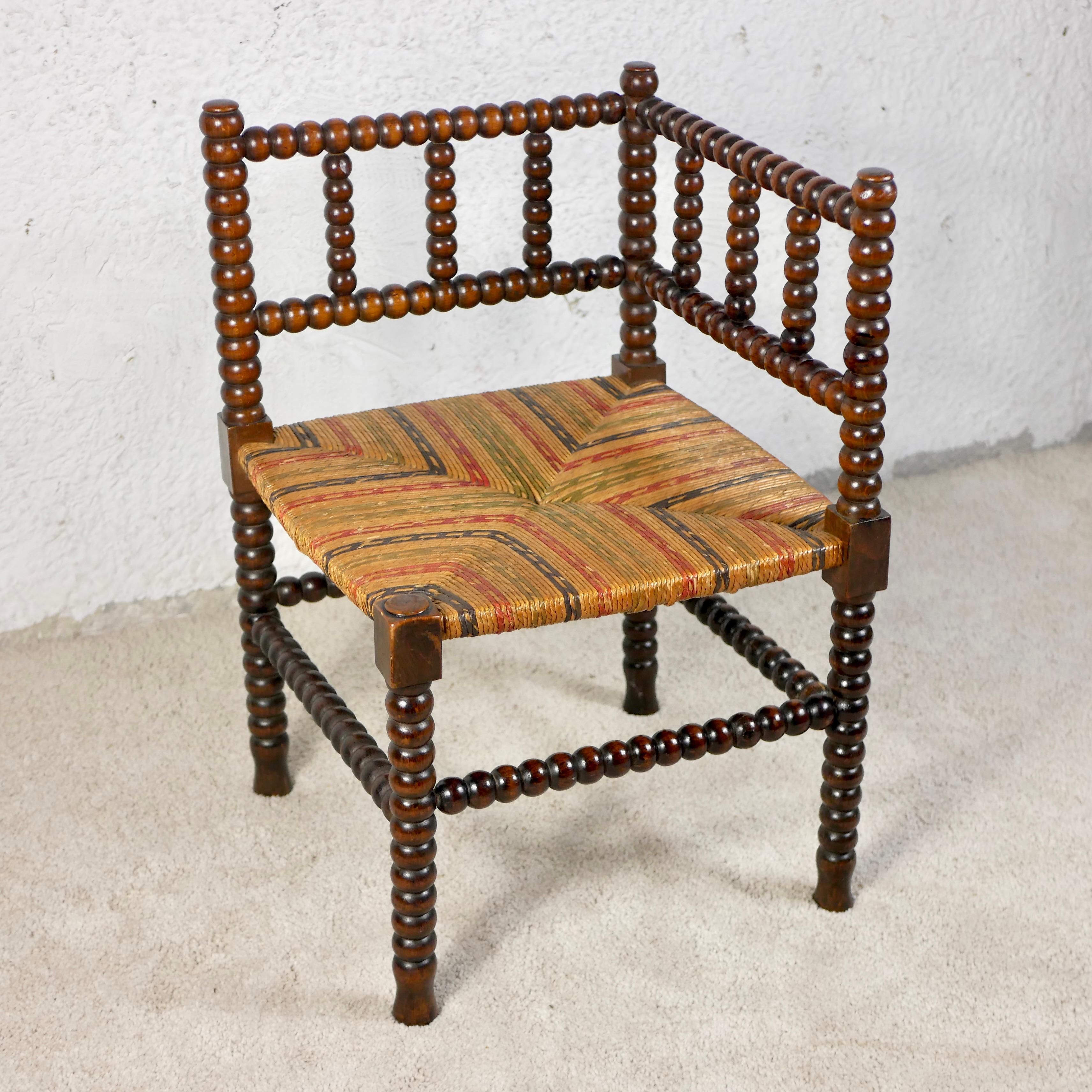 Nice multicolored seat corner chair, also called Bobbin chair, made in France between the second half of the 19th century and the beginning of the 20th century. 
Bobbin chairs were common pieces of furniture especially in the countryside and were